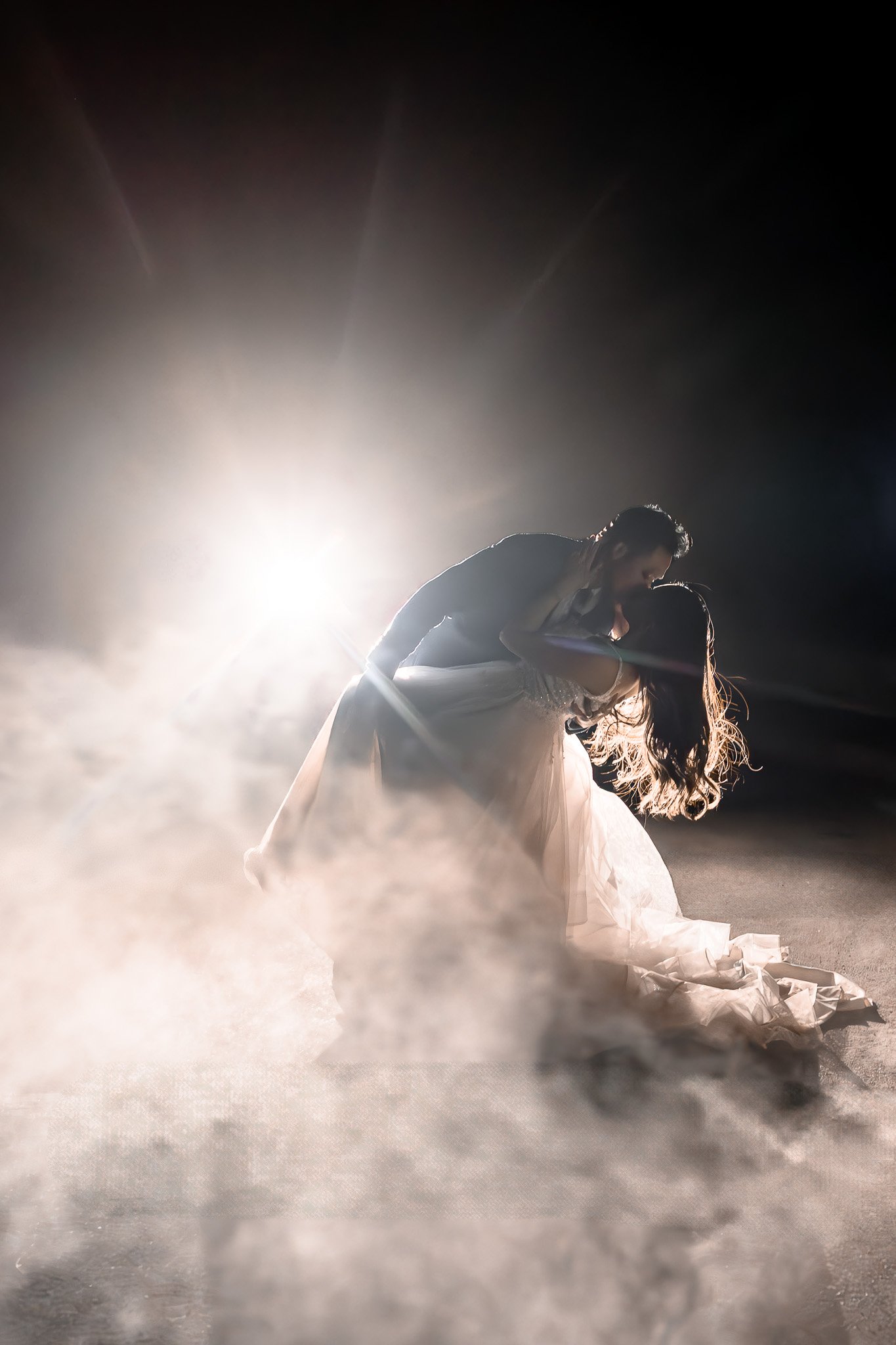 bride and groom at night in front of car headlights with smoke