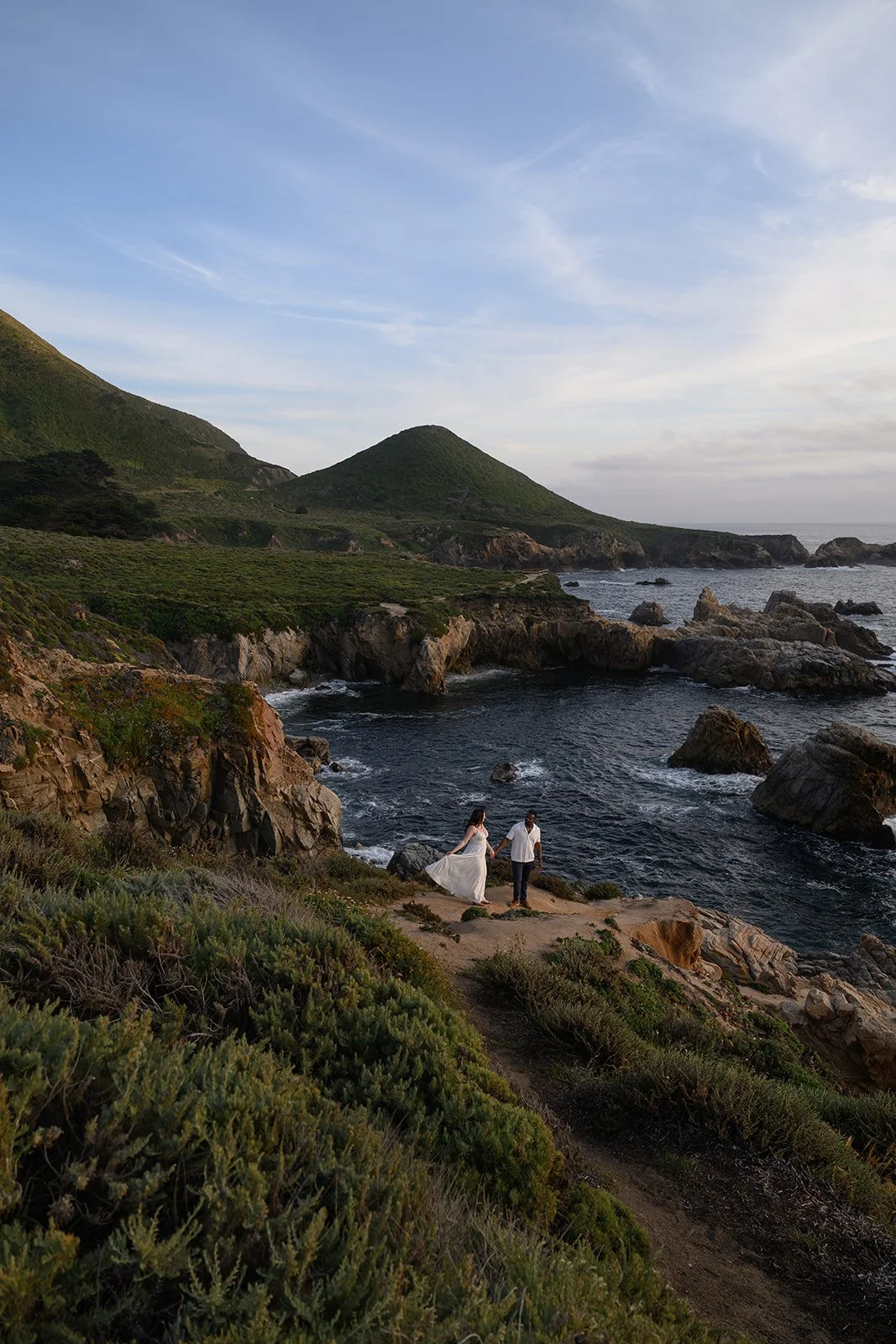 a bride and groom on a cliffside in big sur on their wedding day