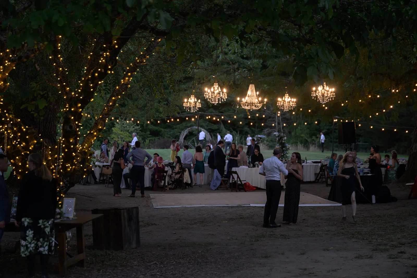 a wedding reception at night on the dance floor at Sydalyn hill with the chandeliers hanging from the trees