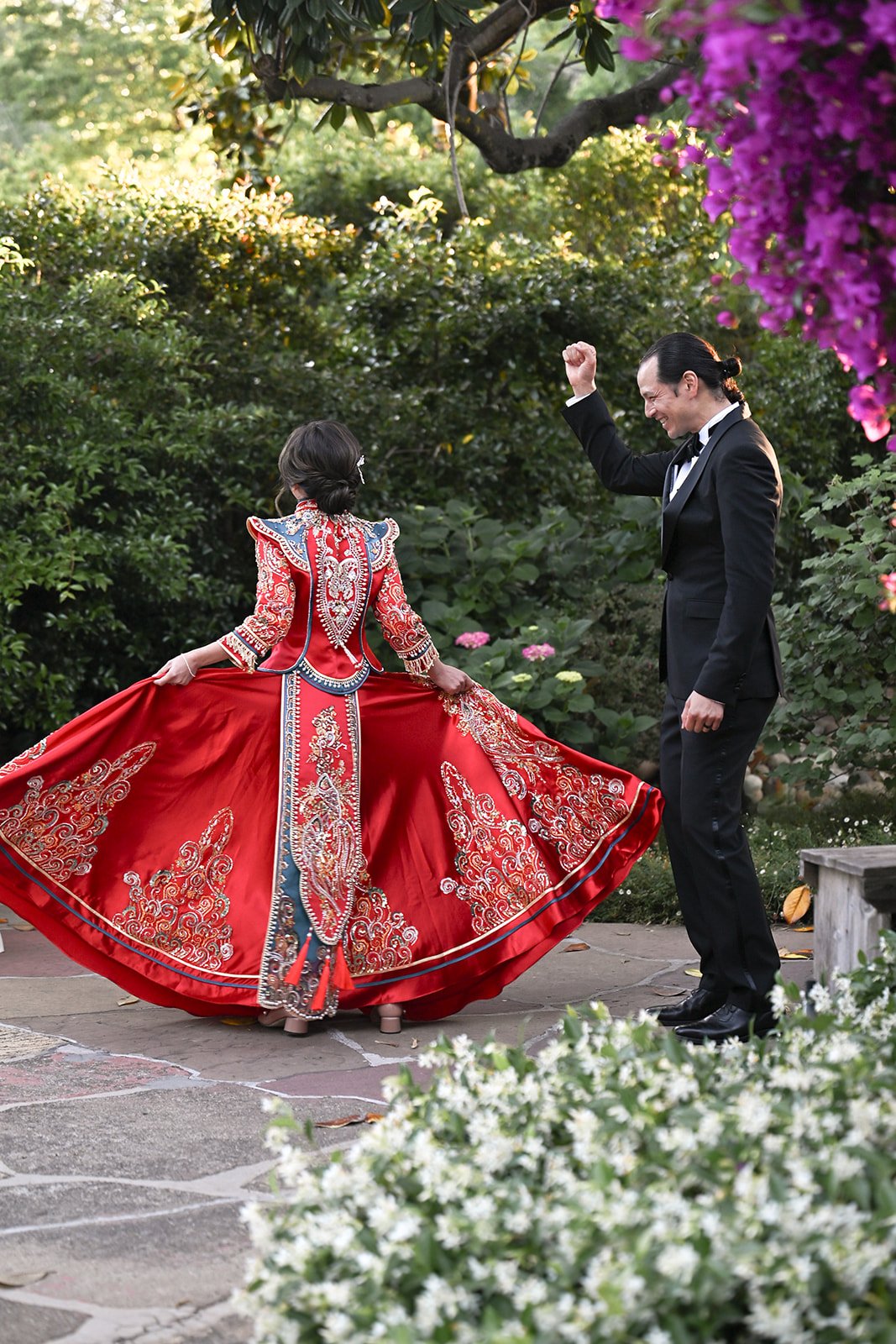 A bride in a traditional red Chinese wedding dress next to the groom at their wedding