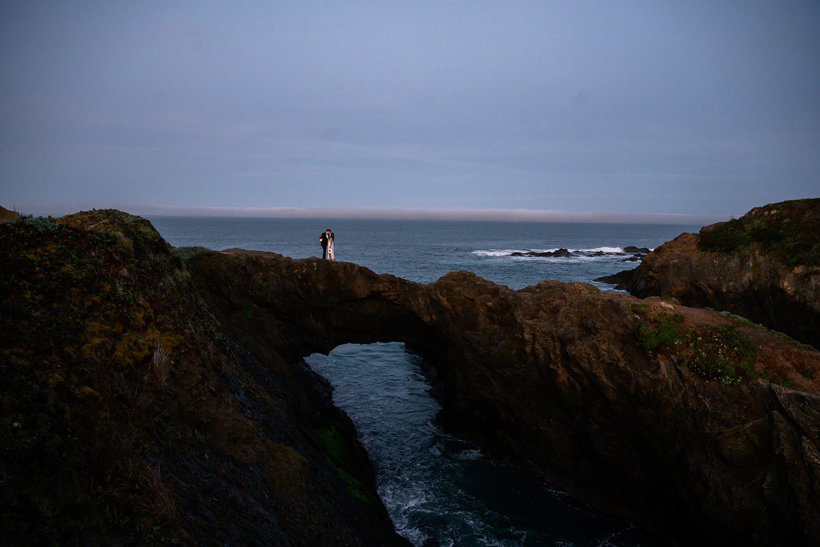 a bride and a groom on a natural bridge by the coast in Mendocino, california
