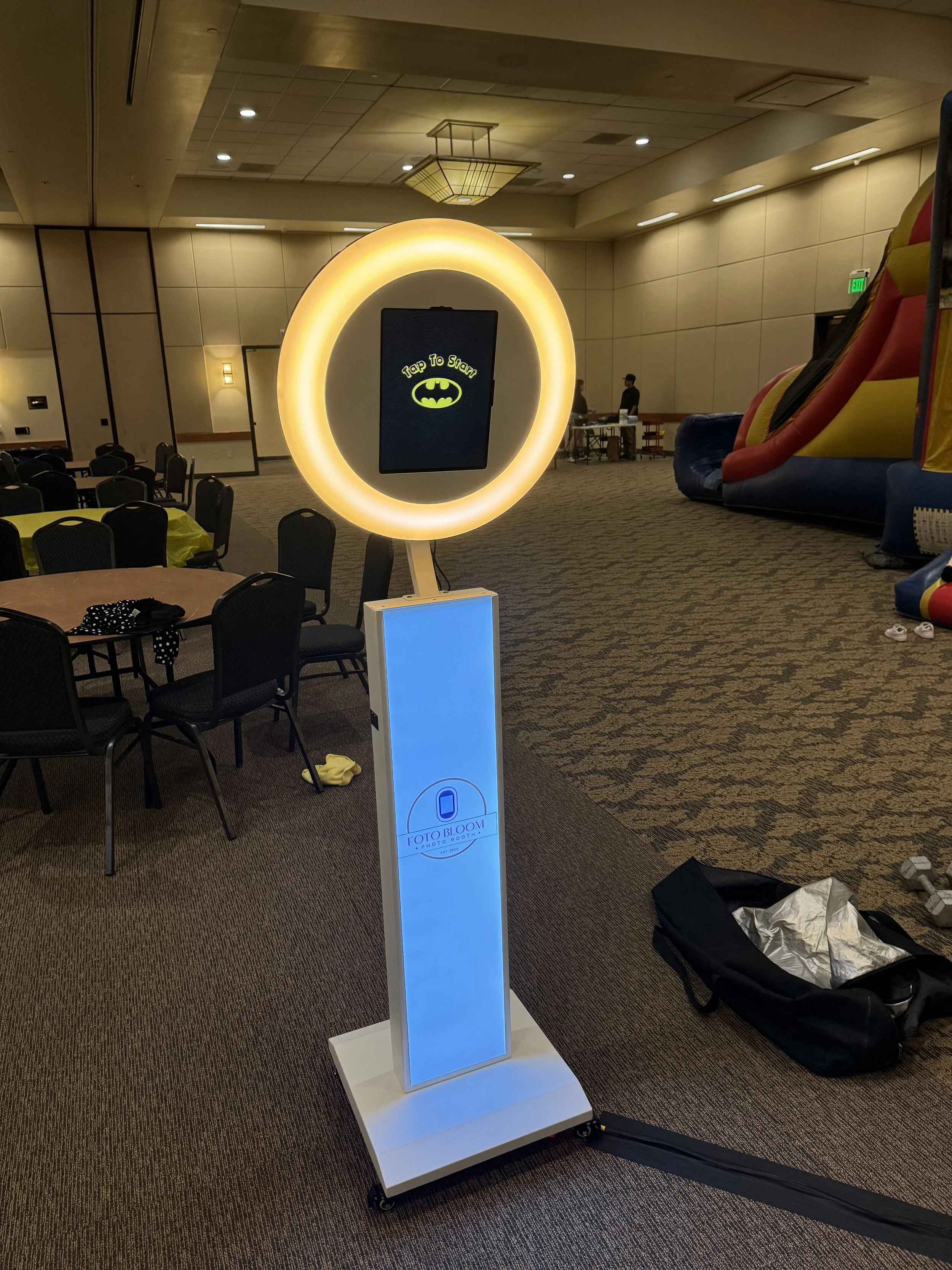 Two smiling women wearing hats and sunglasses, each balancing a small pet in a container on their heads outdoors against a clear sky.