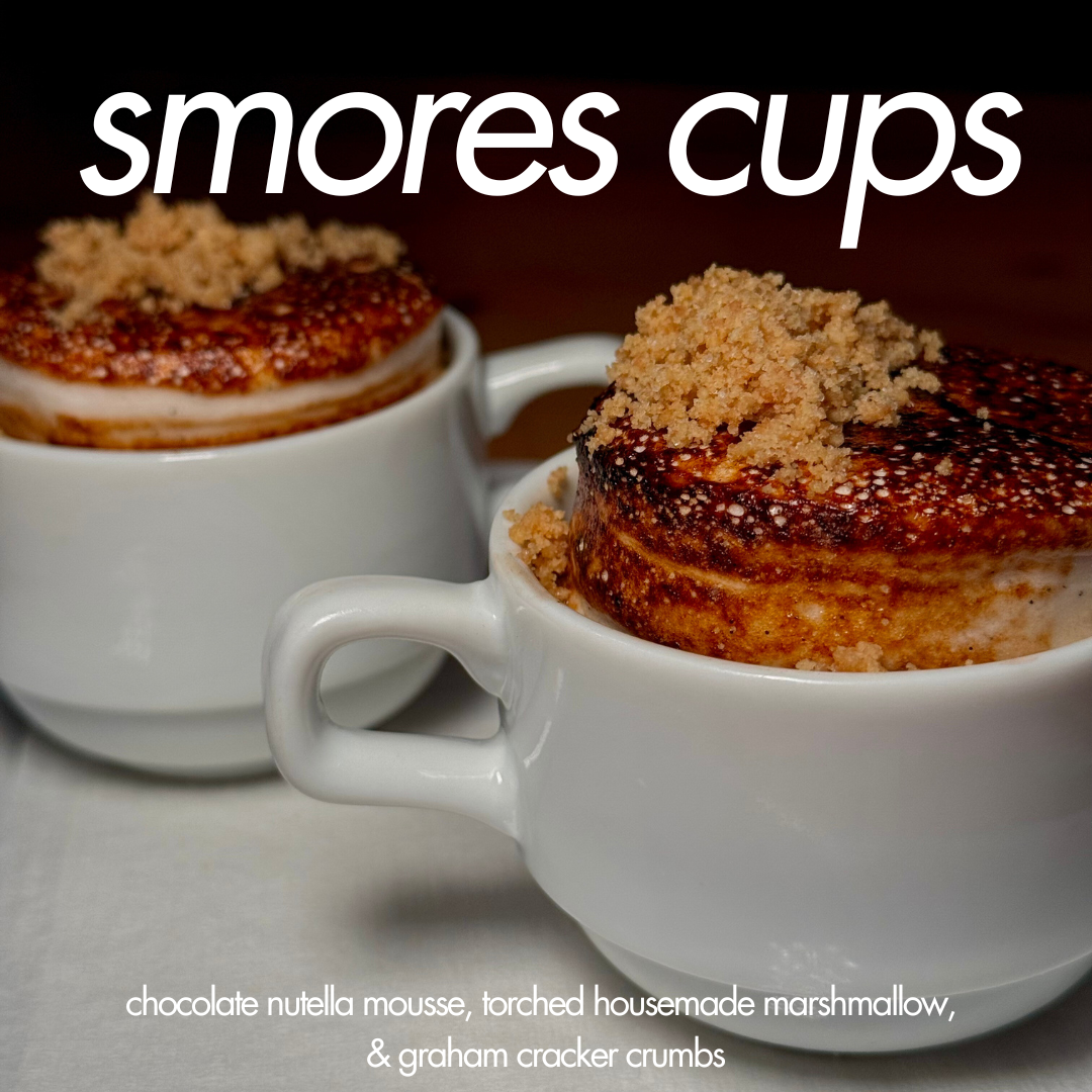 Two white cups filled with s'mores-inspired desserts topped with graham cracker crumbs, with text overlay reading "s'mores cups". Description indicates chocolate Nutella mousse, torched housemade marshmallow, and graham cracker crumbs.