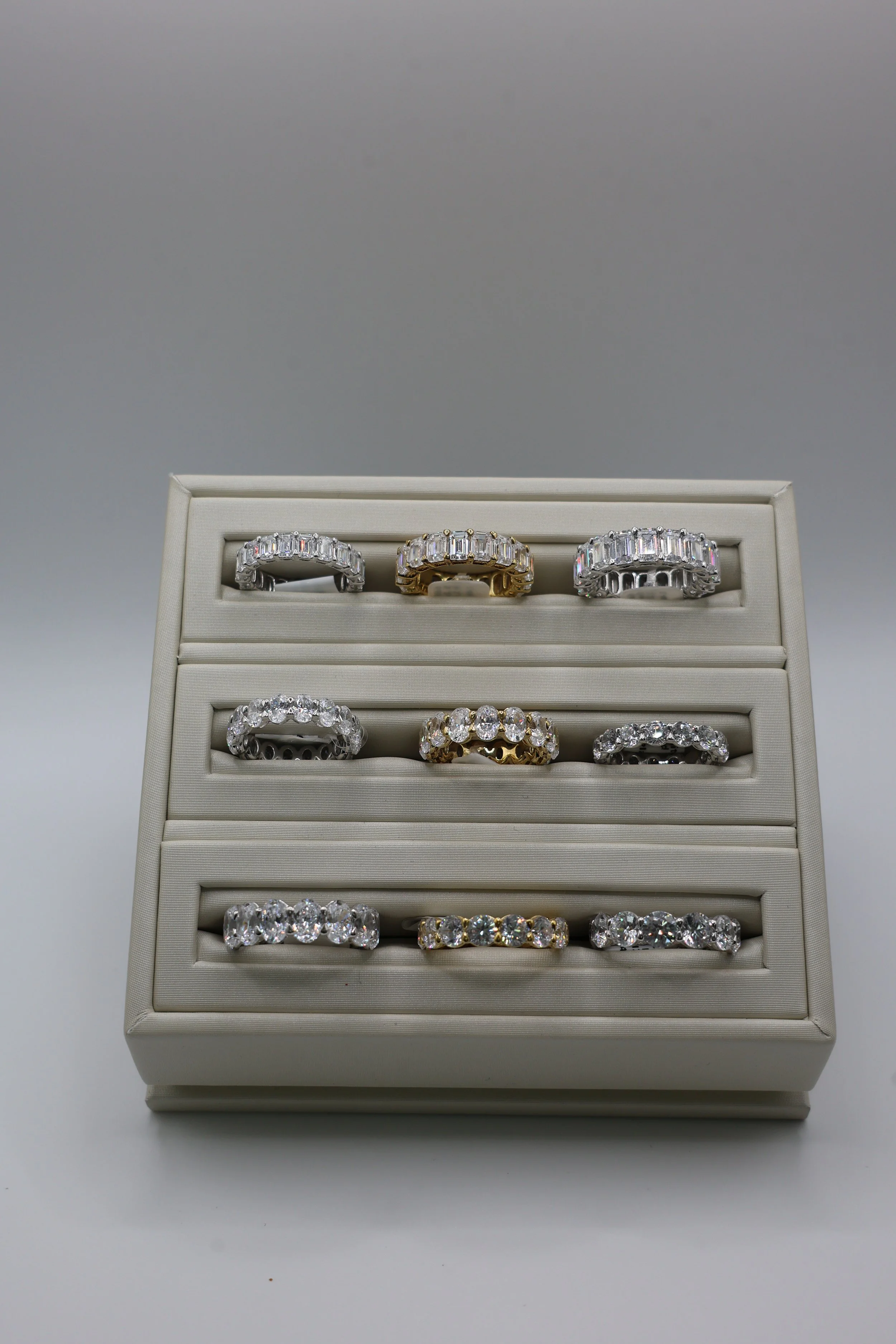 Empty jewelry display case with multiple diamond rings arranged in three rows.