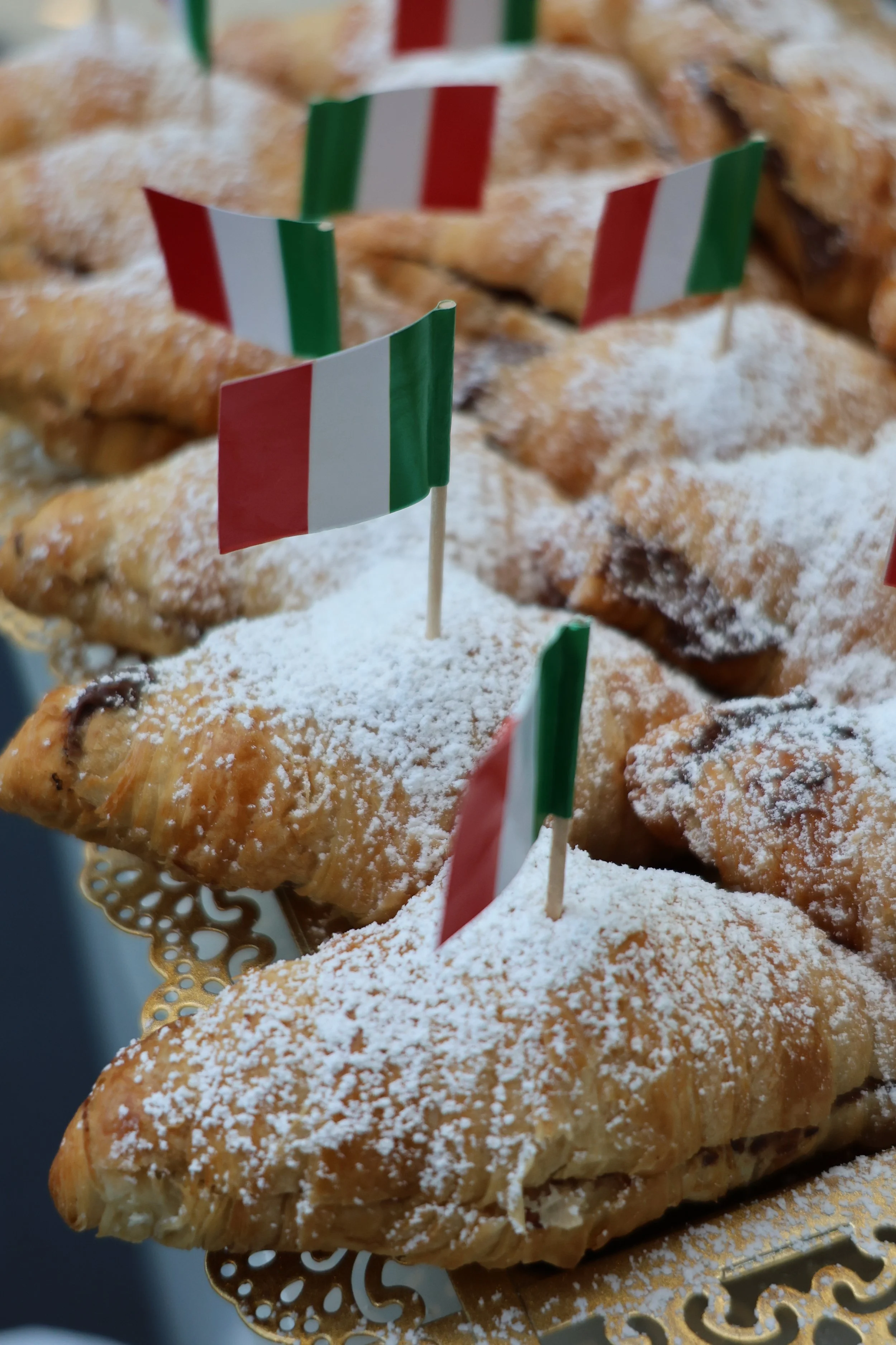 Pastries with powdered sugar and small Italian flags.