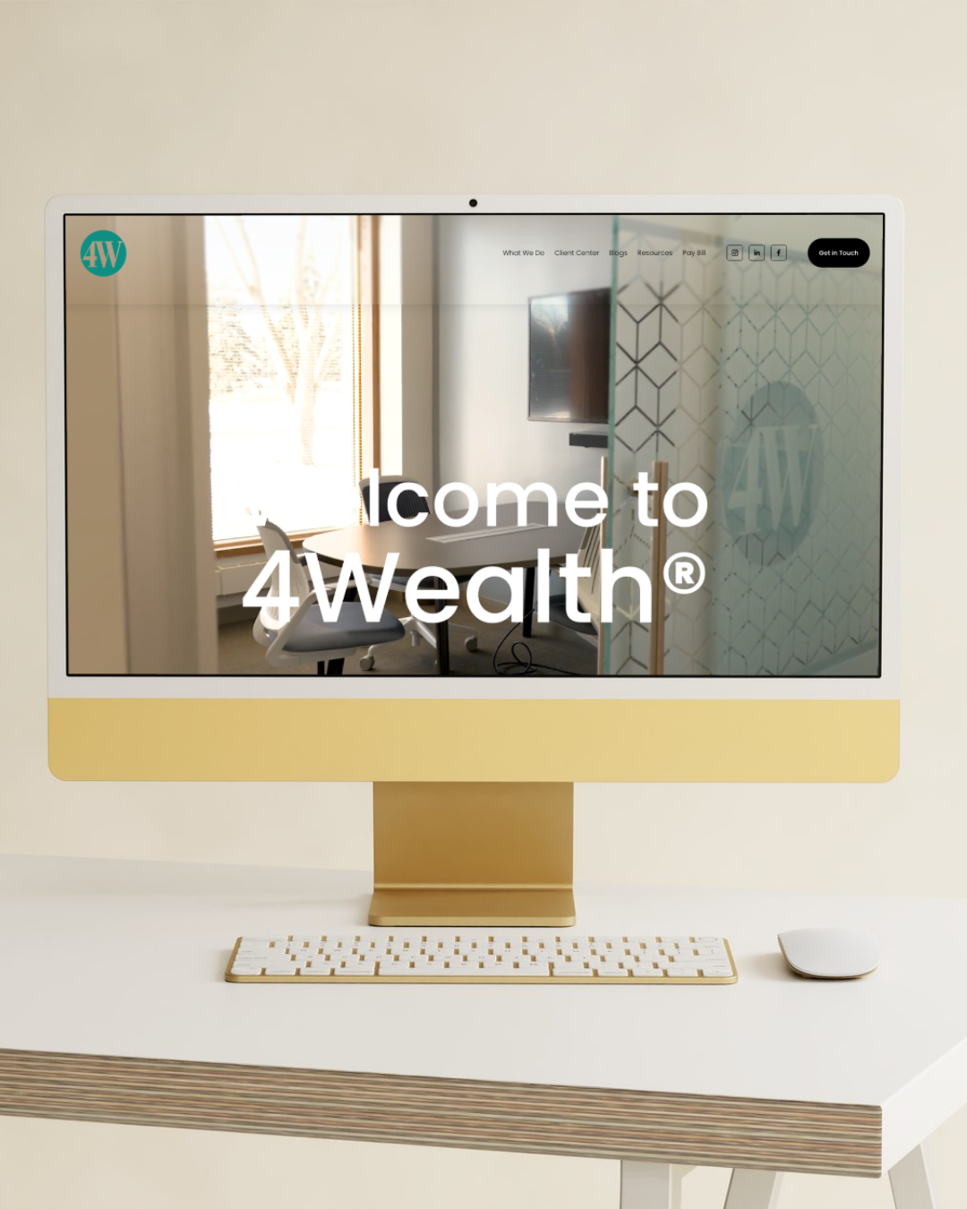 Computer monitor displaying the website 4Wealth with a background of a conference room with a round table, chairs, TV, and window with sunlight.