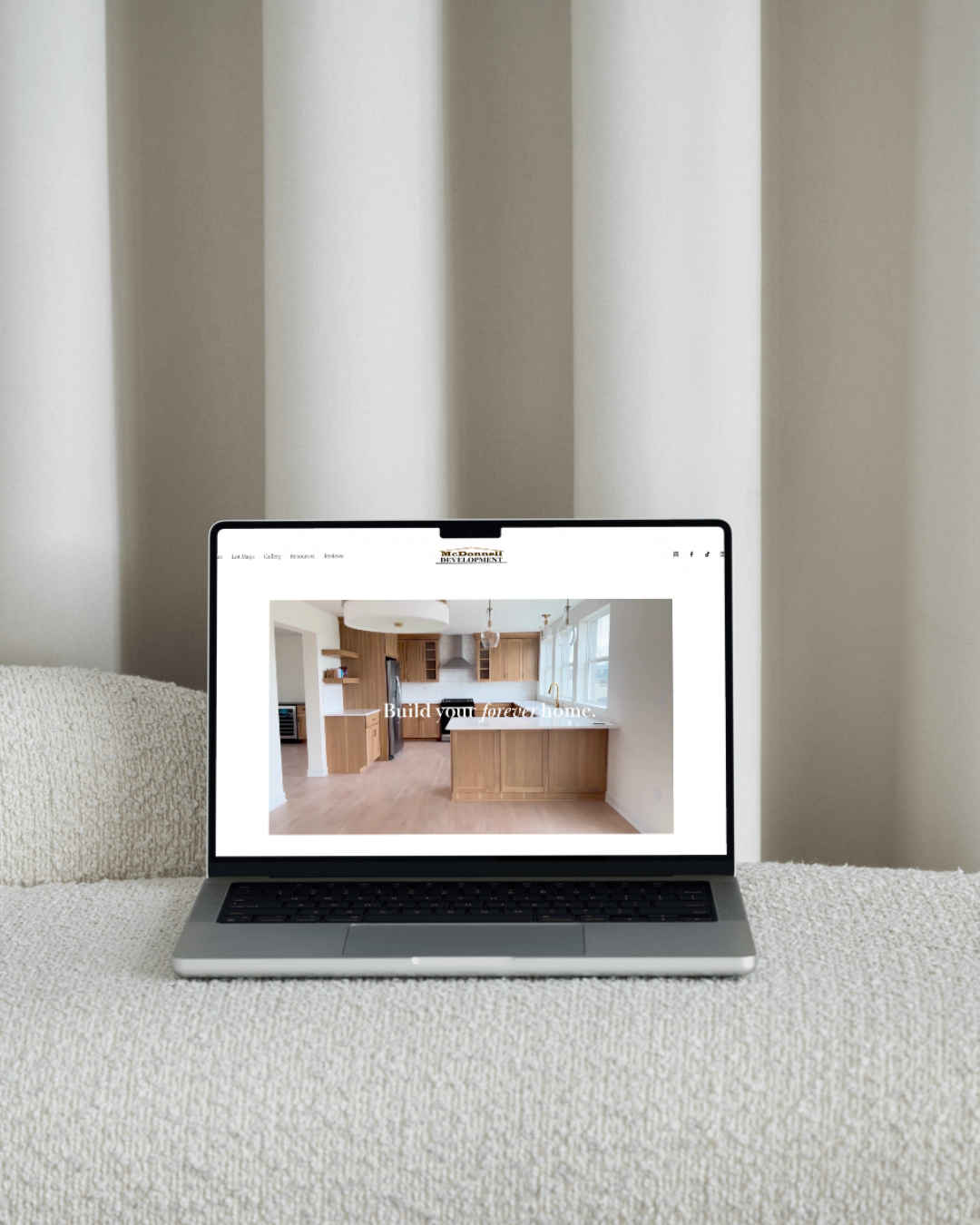 Open laptop displaying a home renovation or construction website with the slogan 'Build your forever home' and an image of a modern kitchen with wooden cabinets and white countertops.