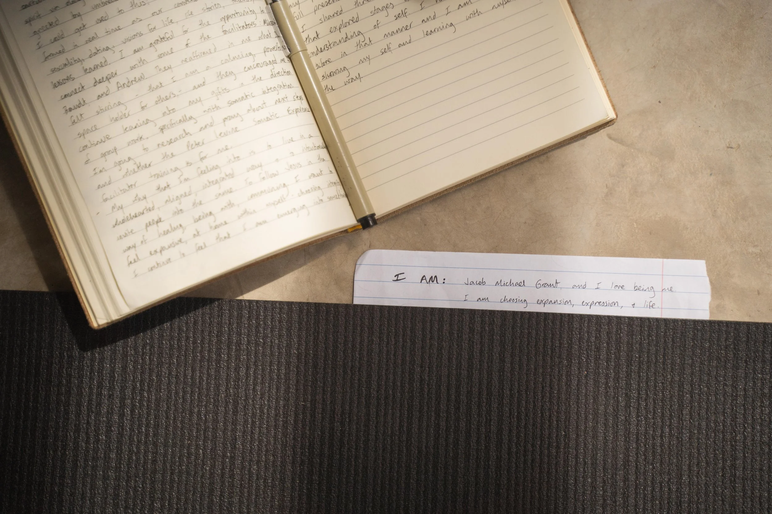 Open journal with handwritten reflections and an affirmation card reading ‘I AM,’ used during a men’s retreat for somatic practices, mindfulness, and emotional expression.