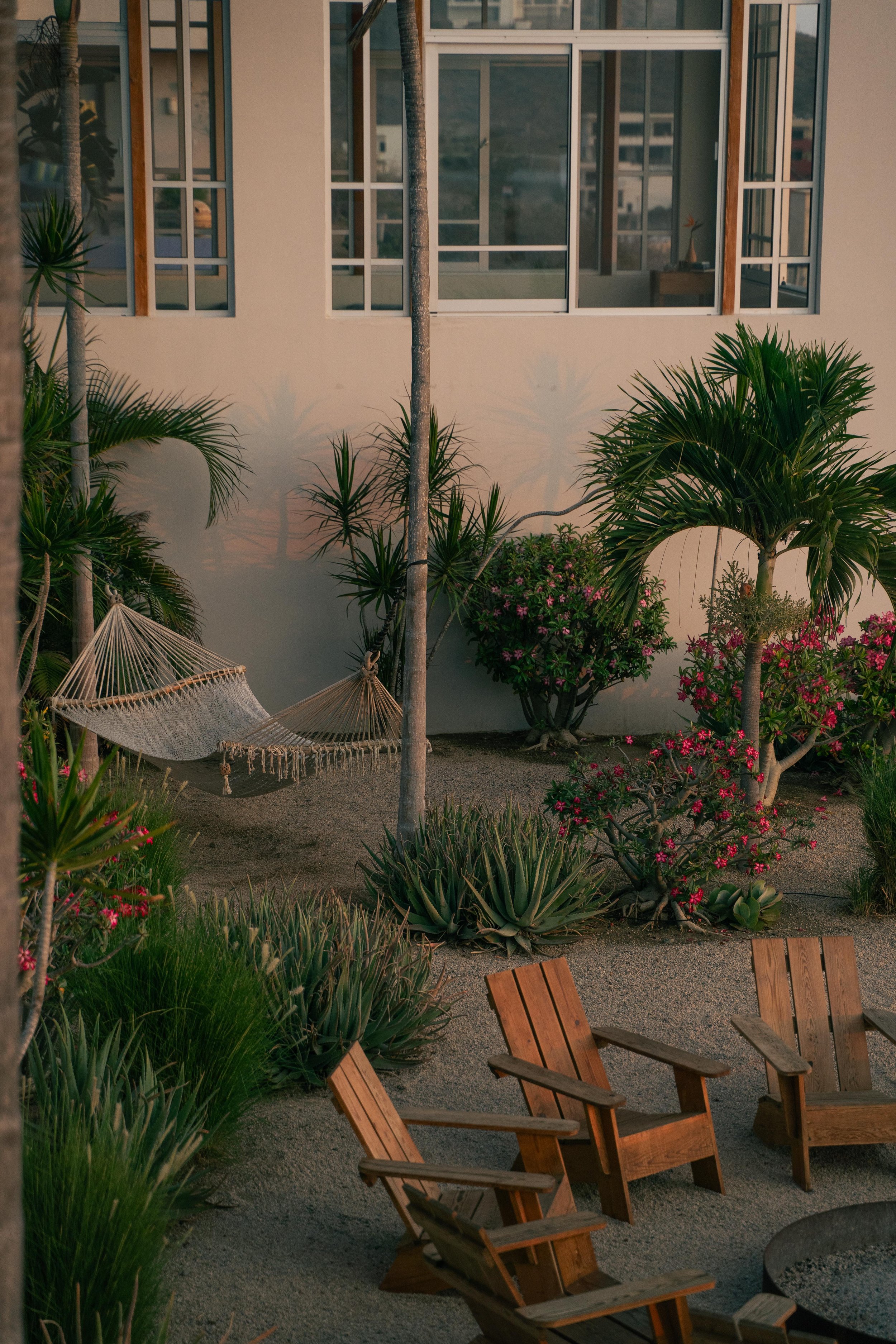 Garden space with hammock, lush greenery, and wooden chairs around a fire pit at SHIFT Men’s Retreat, a somatic wellness retreat for men offering rest, reflection, and connection.