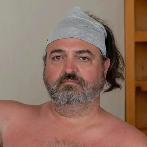 A millennial man looking pensive as a demonstration happens at a somatic retreat for men in Baja California.