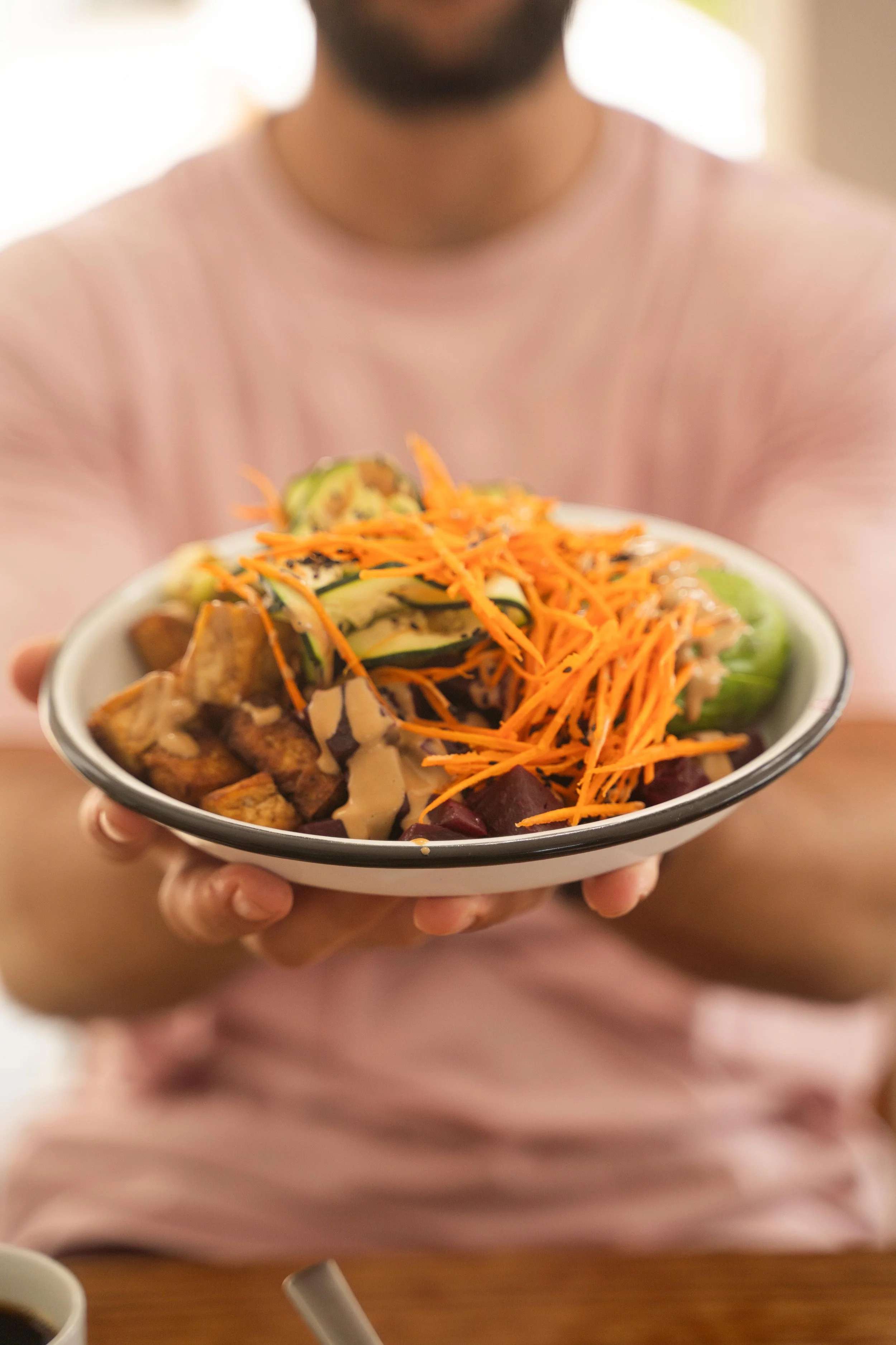 Healthy plant-based meal with roasted vegetables, avocado, shredded carrots, and tahini dressing, served at a somatic men’s retreat to support wellness and nourishment.