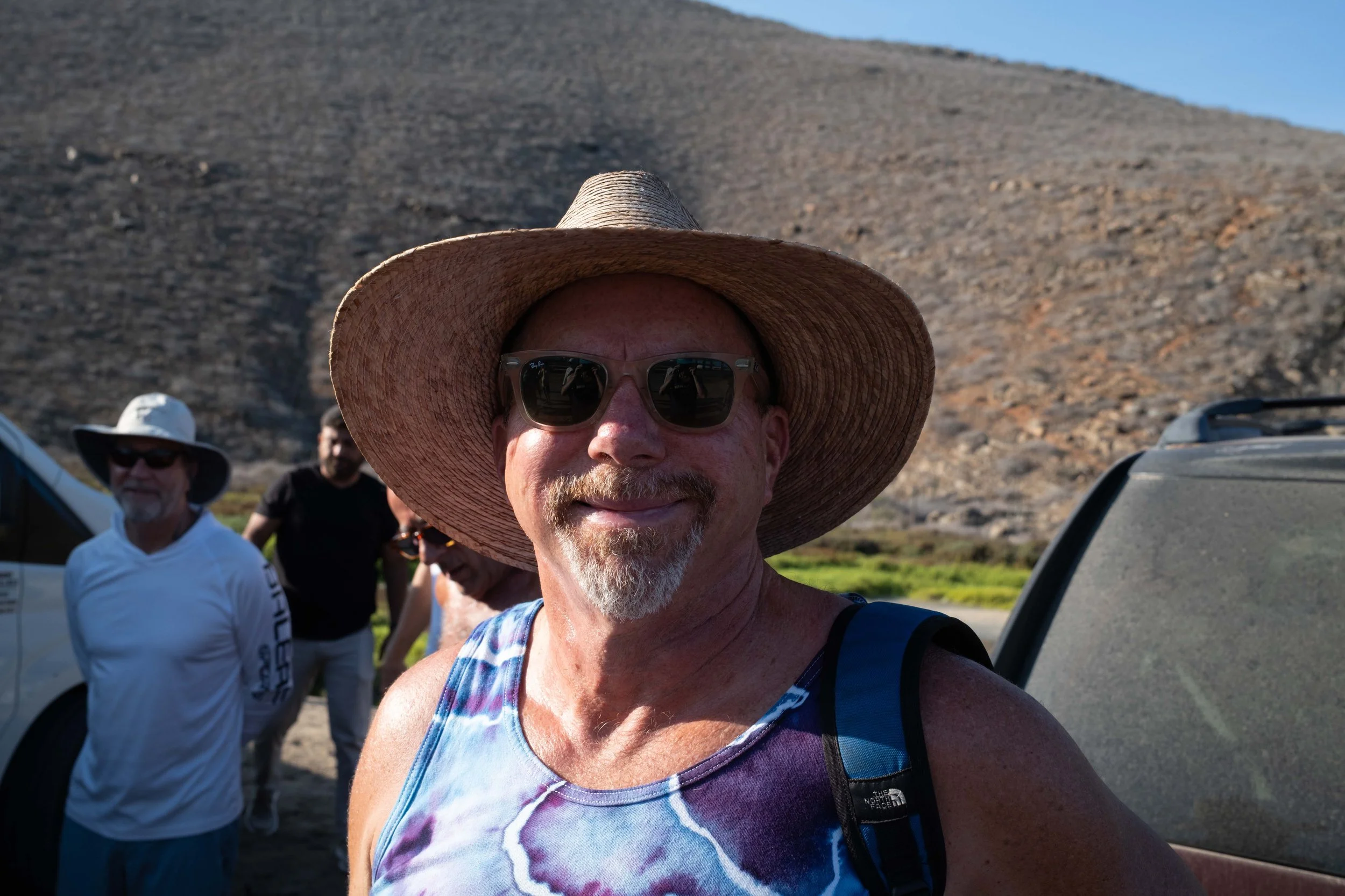 A man in his 60s at a somatic retreat for men in Baja California Mexico smiles at the camera.