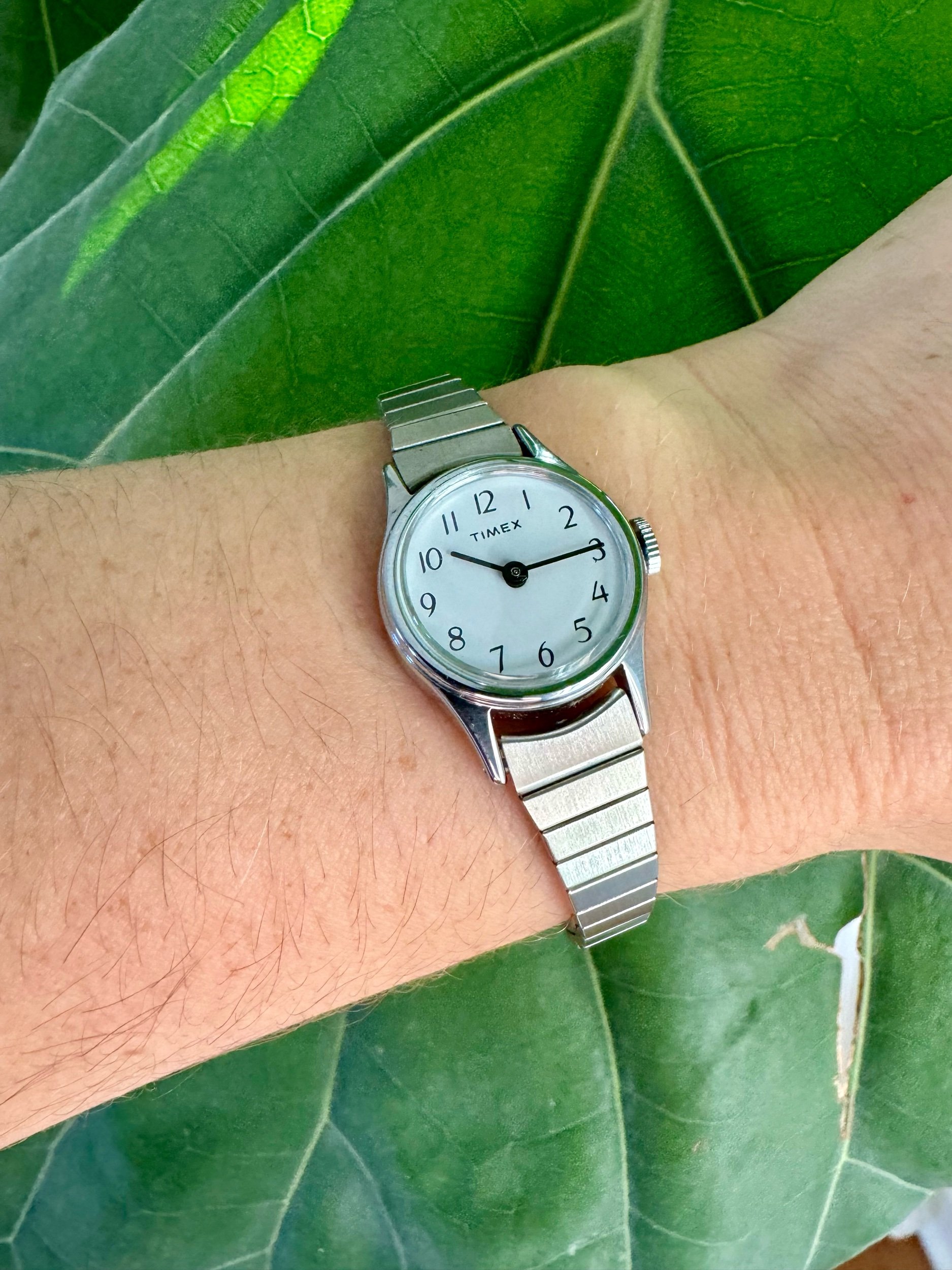 Vintage 1990s silver-tone Timex mechanical watch with stretch band, fits 5-7 inch wrists. Classic retro style, keeps time for 12 hours