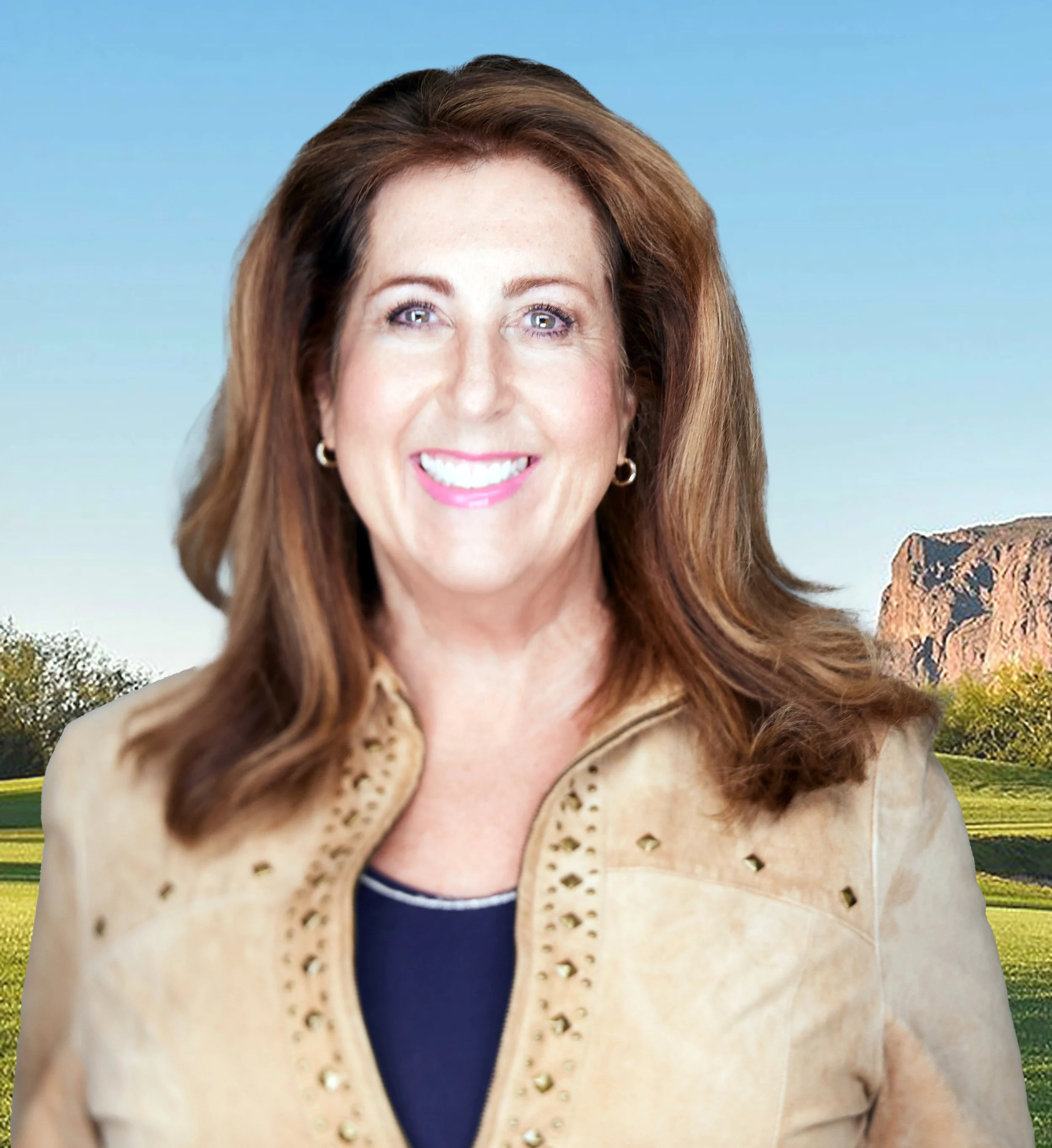 Smiling woman with brown hair and pearl earrings outdoors with blue sky and green landscape in the background.