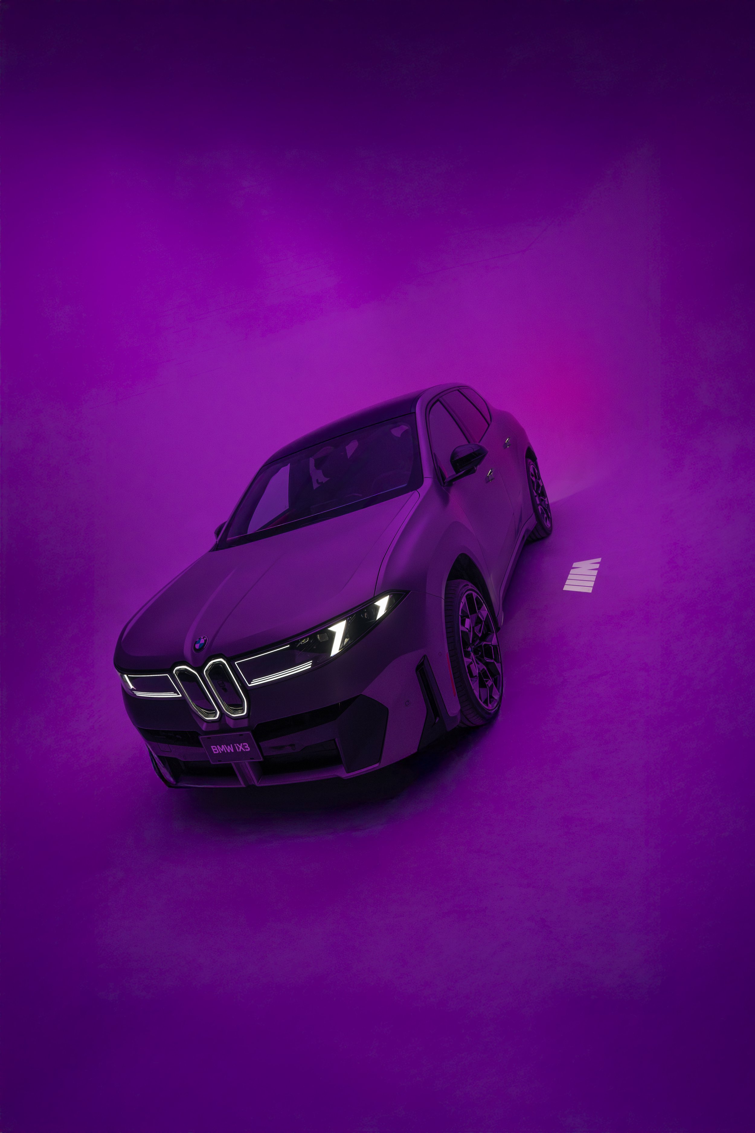 A dark purple BMW X3 M vehicle displayed on a purple surface with purple background lighting.