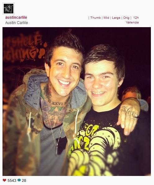 Two young men smiling and hugging each other at a party, with colorful graffiti in the background.