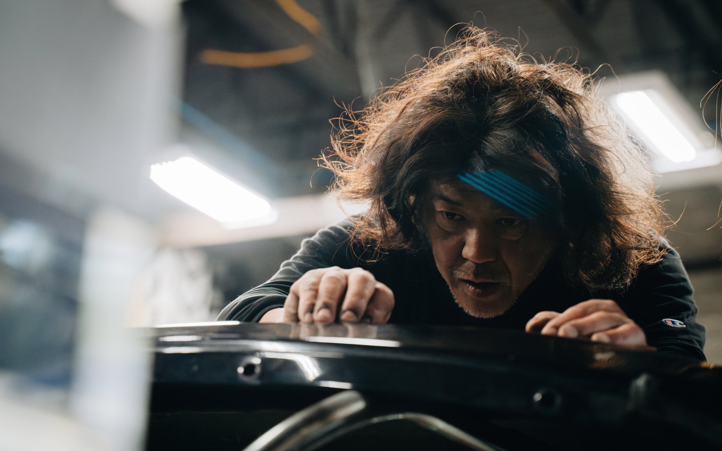 A person with curly hair and a blue headband working out in a gym, focused on an exercise.