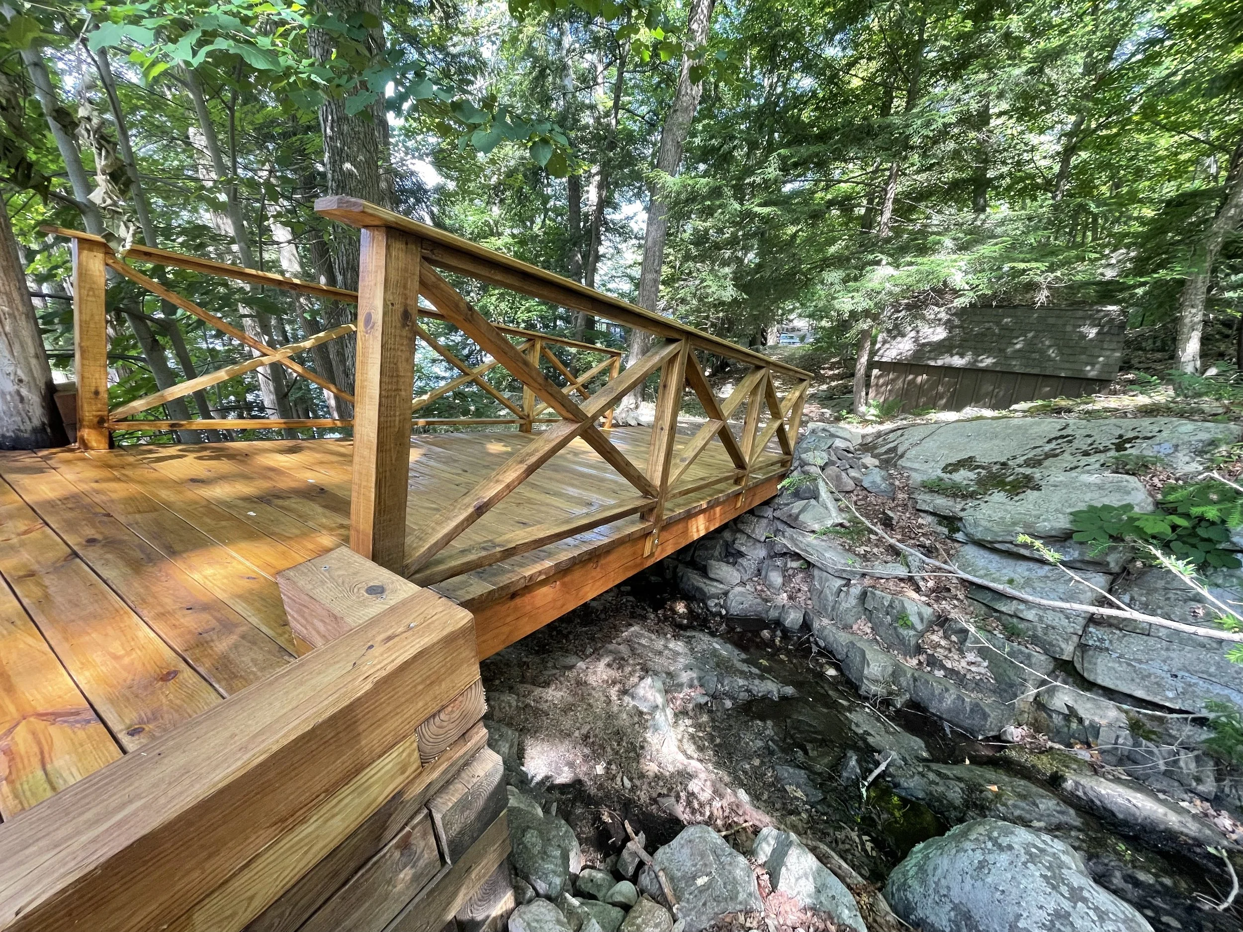 Wooden bridge over a rocky stream in a forested area.
