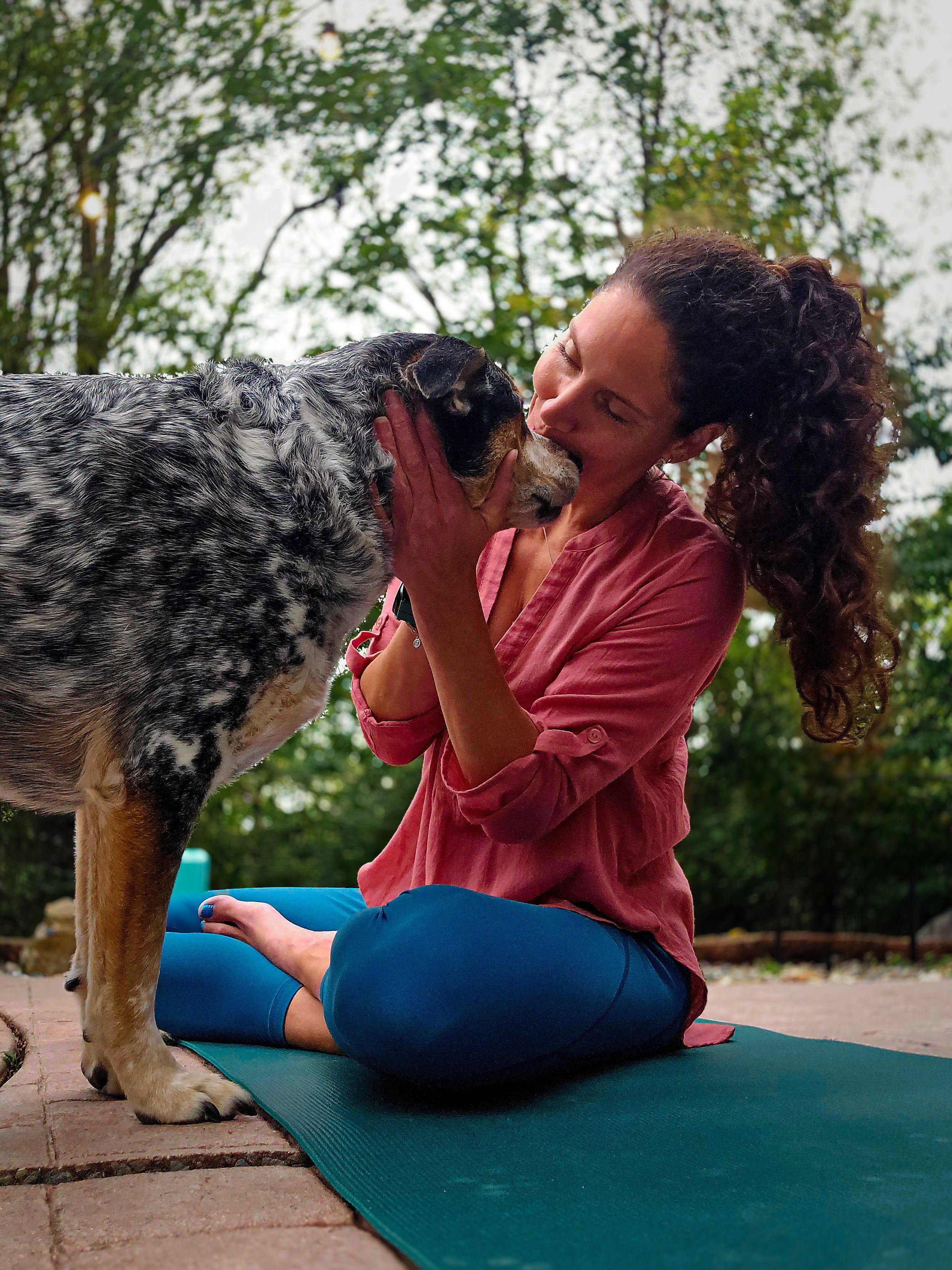 a dog and a women outside on a yoga mat.