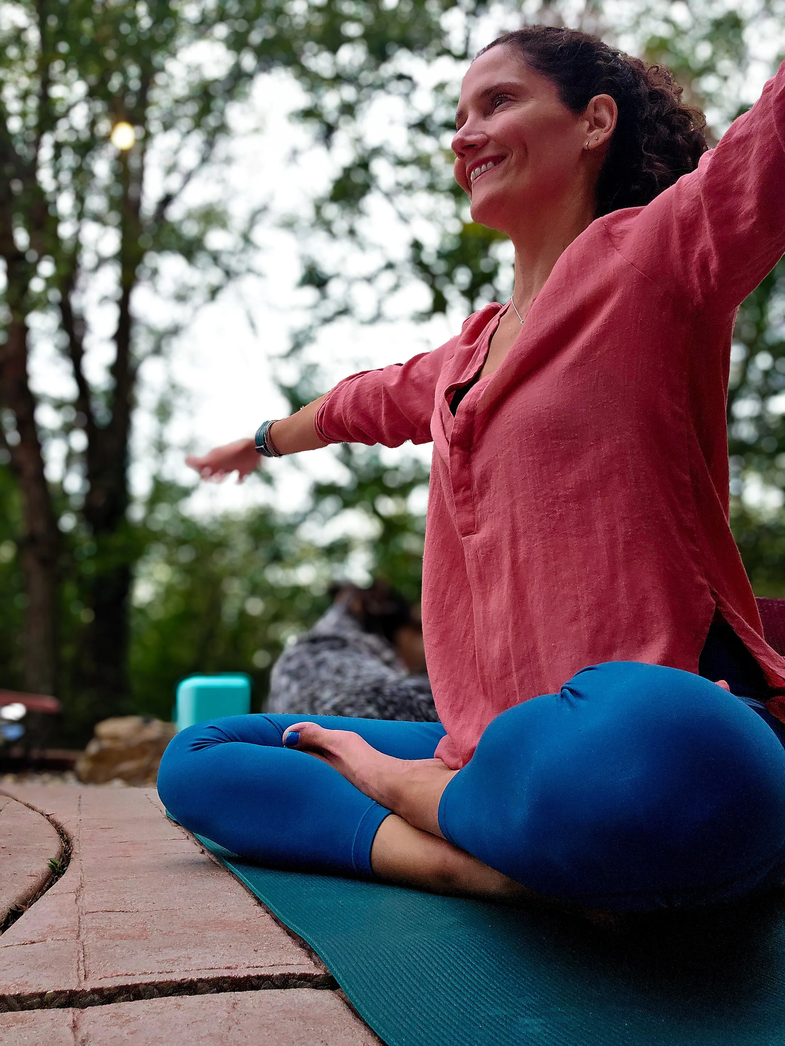 a women with her arms spread out in a tee outside sitting down. 