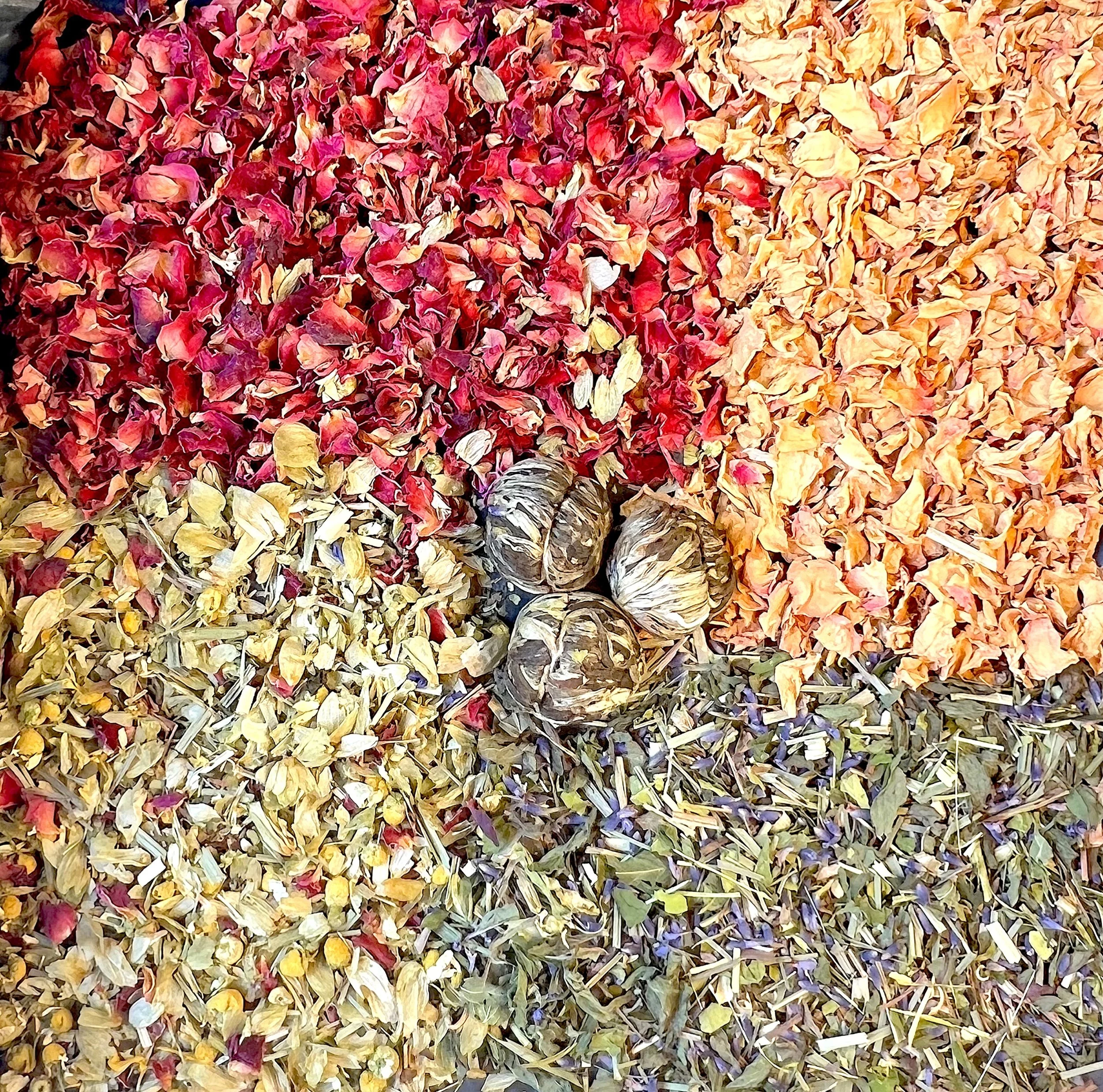 Dreamy gift boxes An assortment of dried flower petals in red, orange, yellow, and purple colors, with three dried seed pods placed in the center.