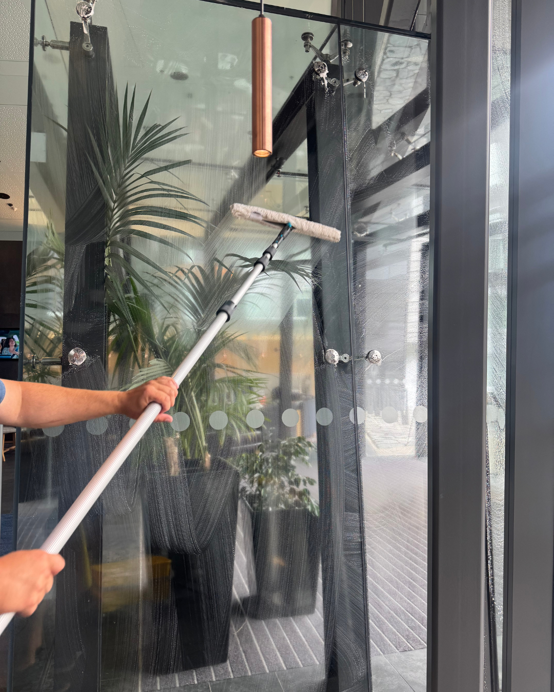 Commercial interior window cleaning with a squeegee removing fingerprints and marks from glass doors.