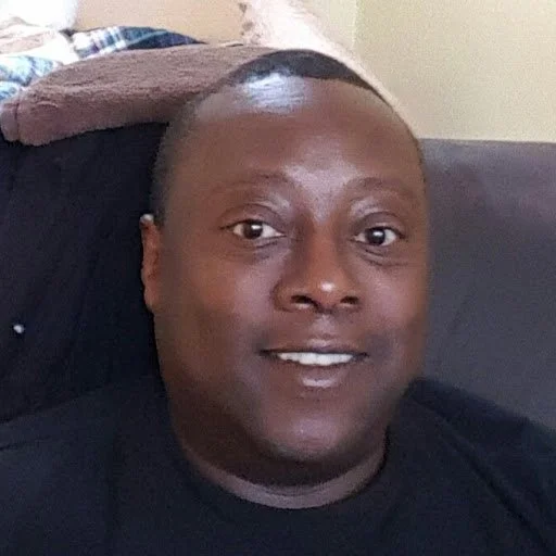 A man lying on a couch, smiling at the camera.