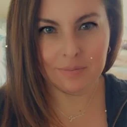 Close-up of a woman with shoulder-length brown hair and blue eyes, smiling softly.