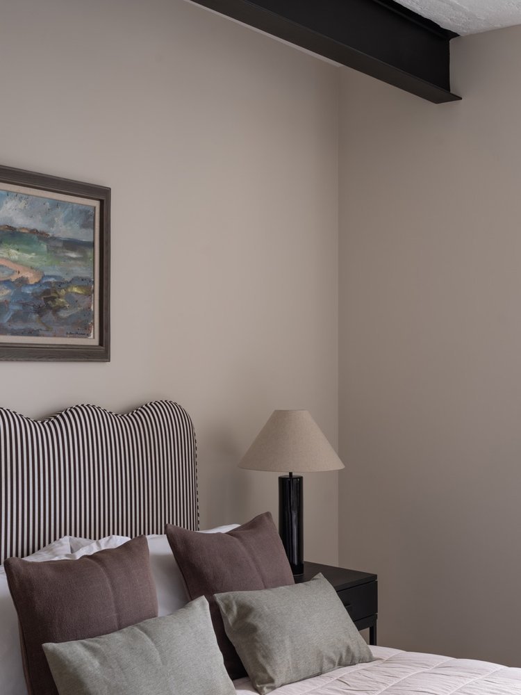 Bedroom corner with a striped headboard, pillows, a nightstand, and a lamp.