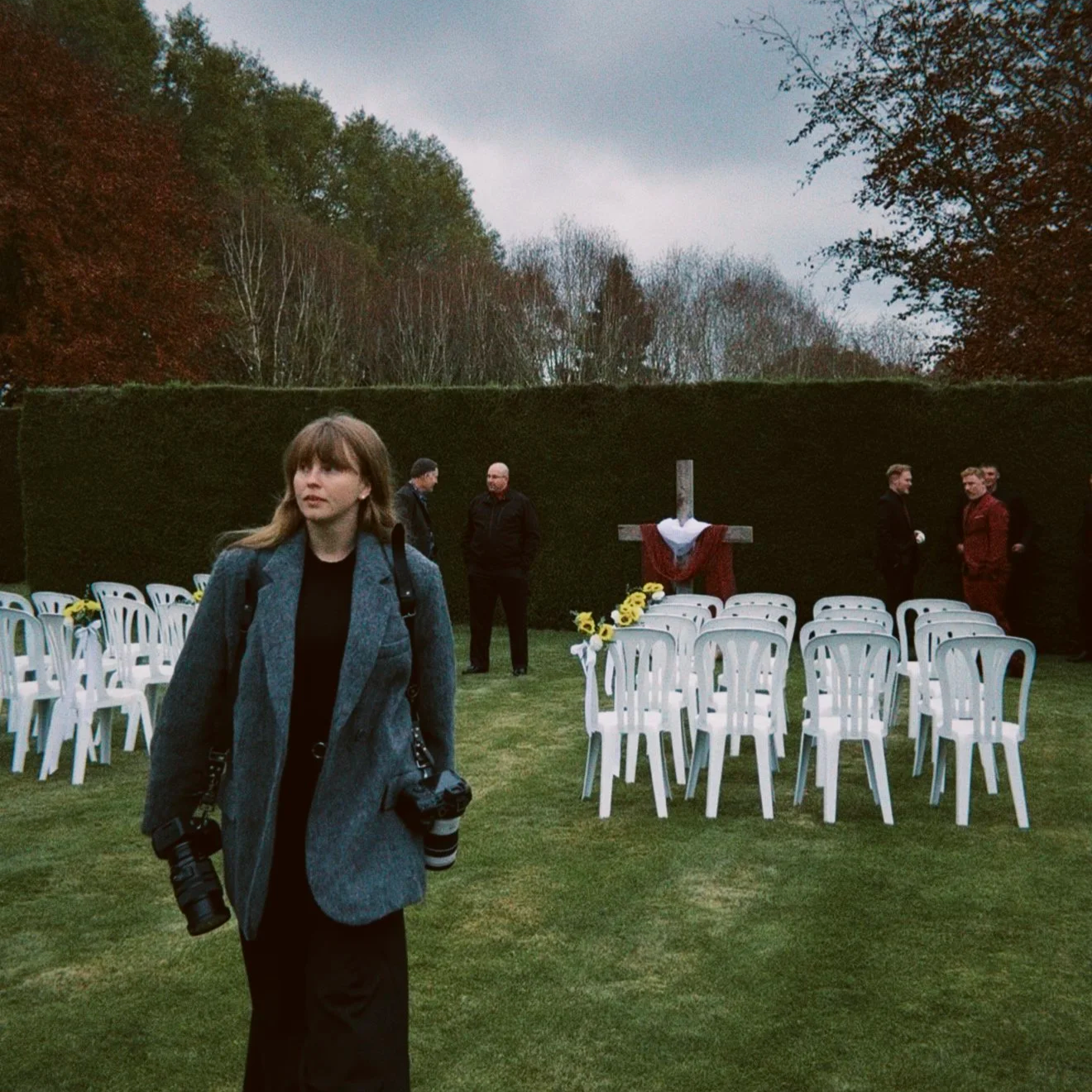 Wedding photographer walking past ceremony chairs in the garden at Trott’s Garden