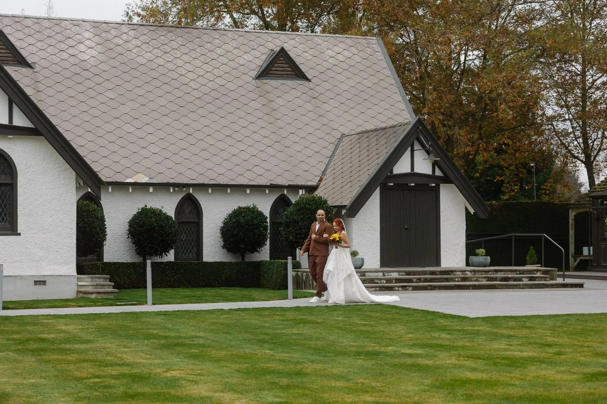 Bride and family member walking past the white venue building at Trott’s Garden