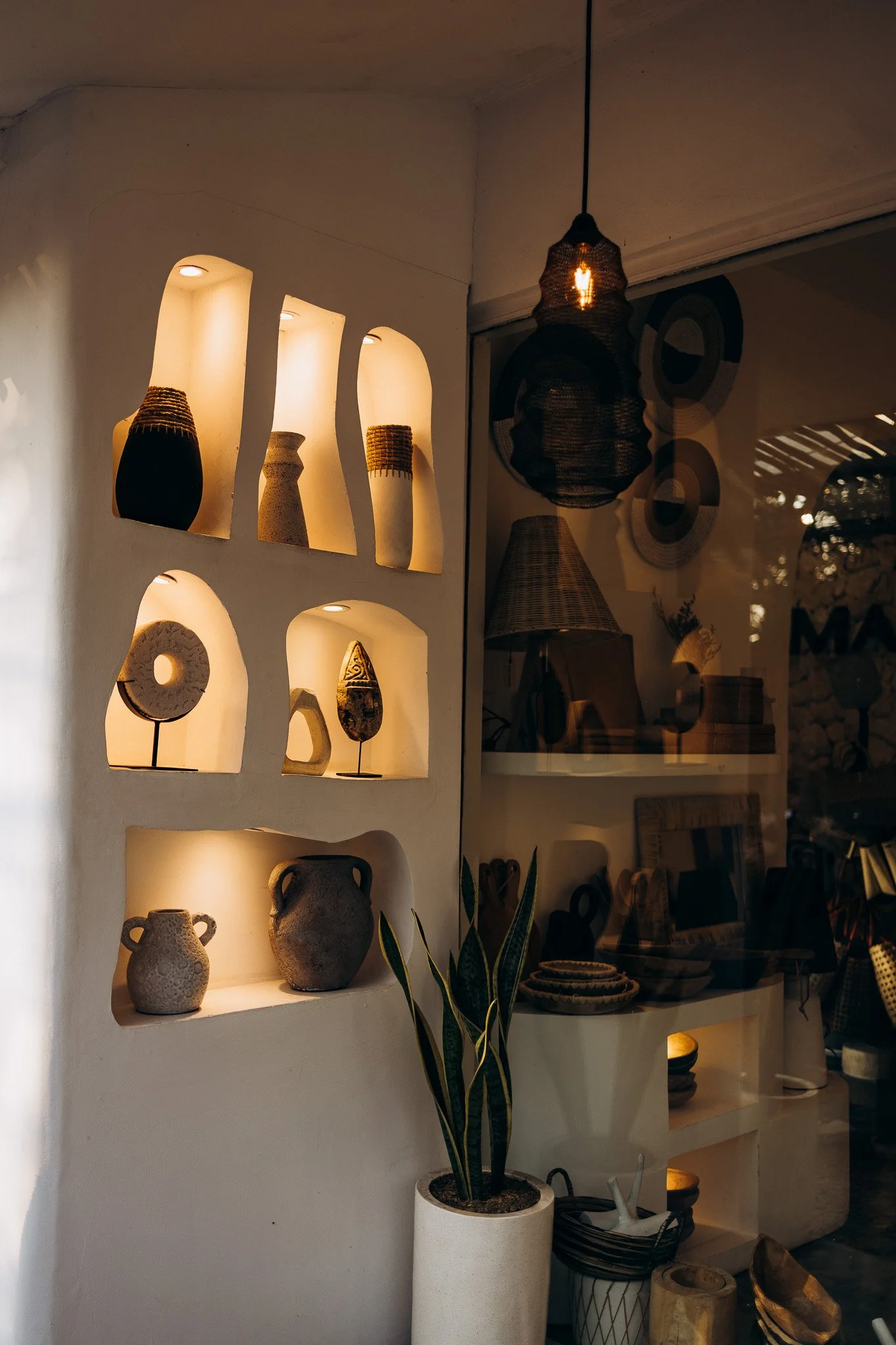 Llamas and sheep grazing in a grassy field with trees and mountains in the background.