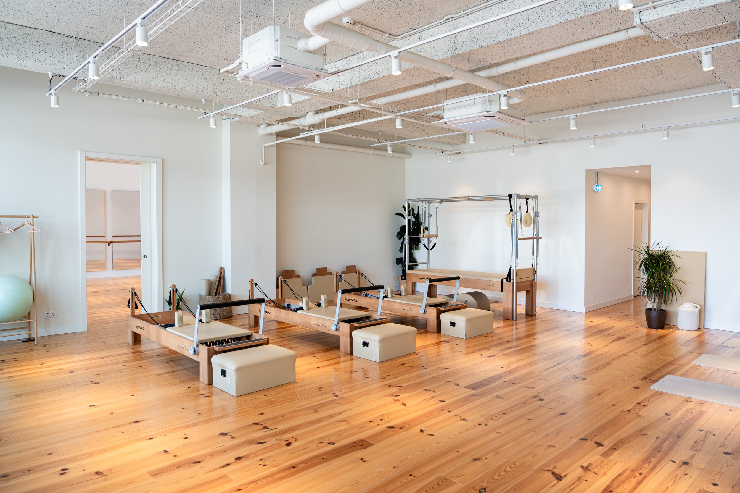 Ambiente do Plenum Studio durante uma aula de Pilates em Lisboa, com exercícios realizados em Reformer, Cadillac e Wall Units para melhorar força, postura e bem-estar.