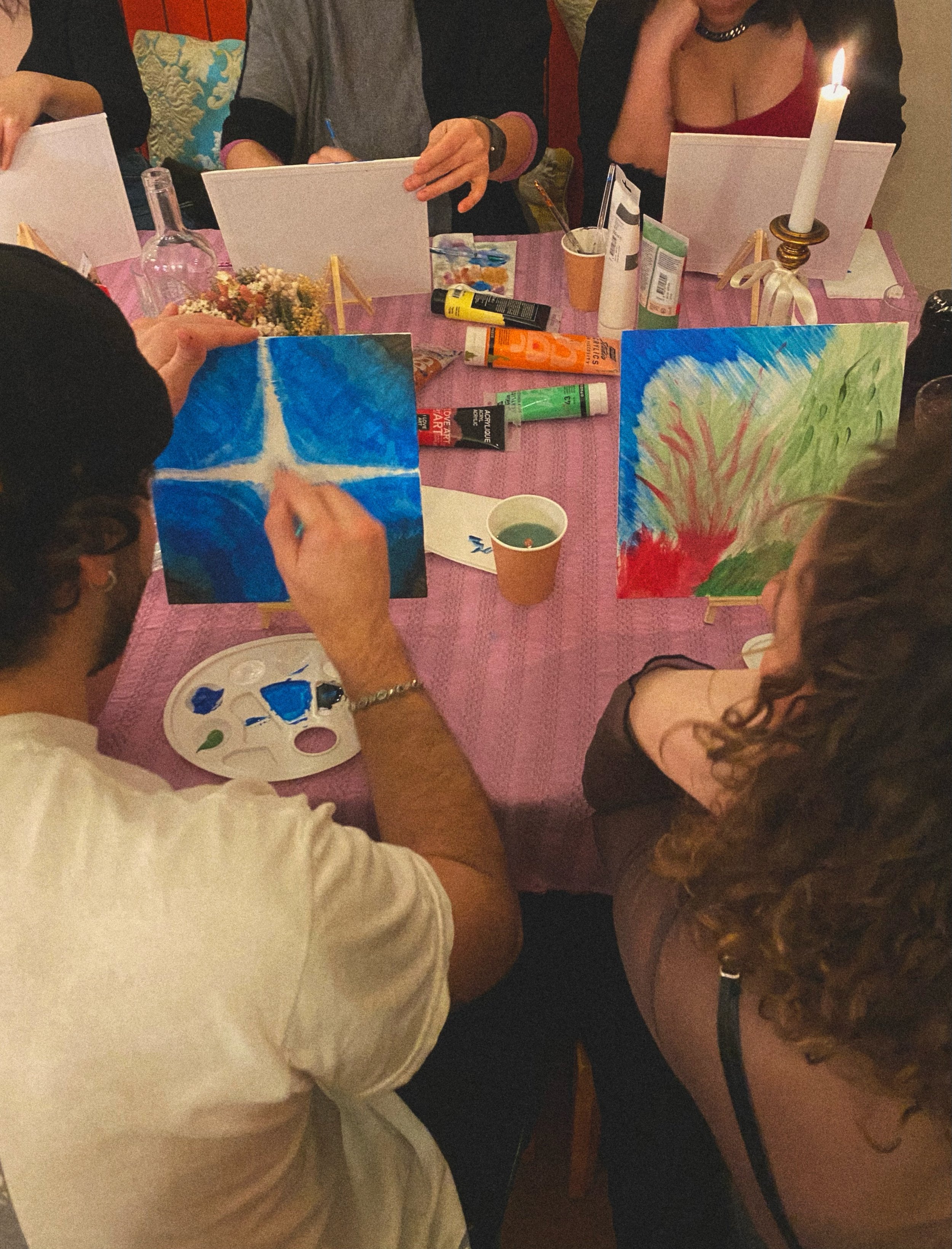 Personnes peignant autour d'une table avec des fournitures artistiques.