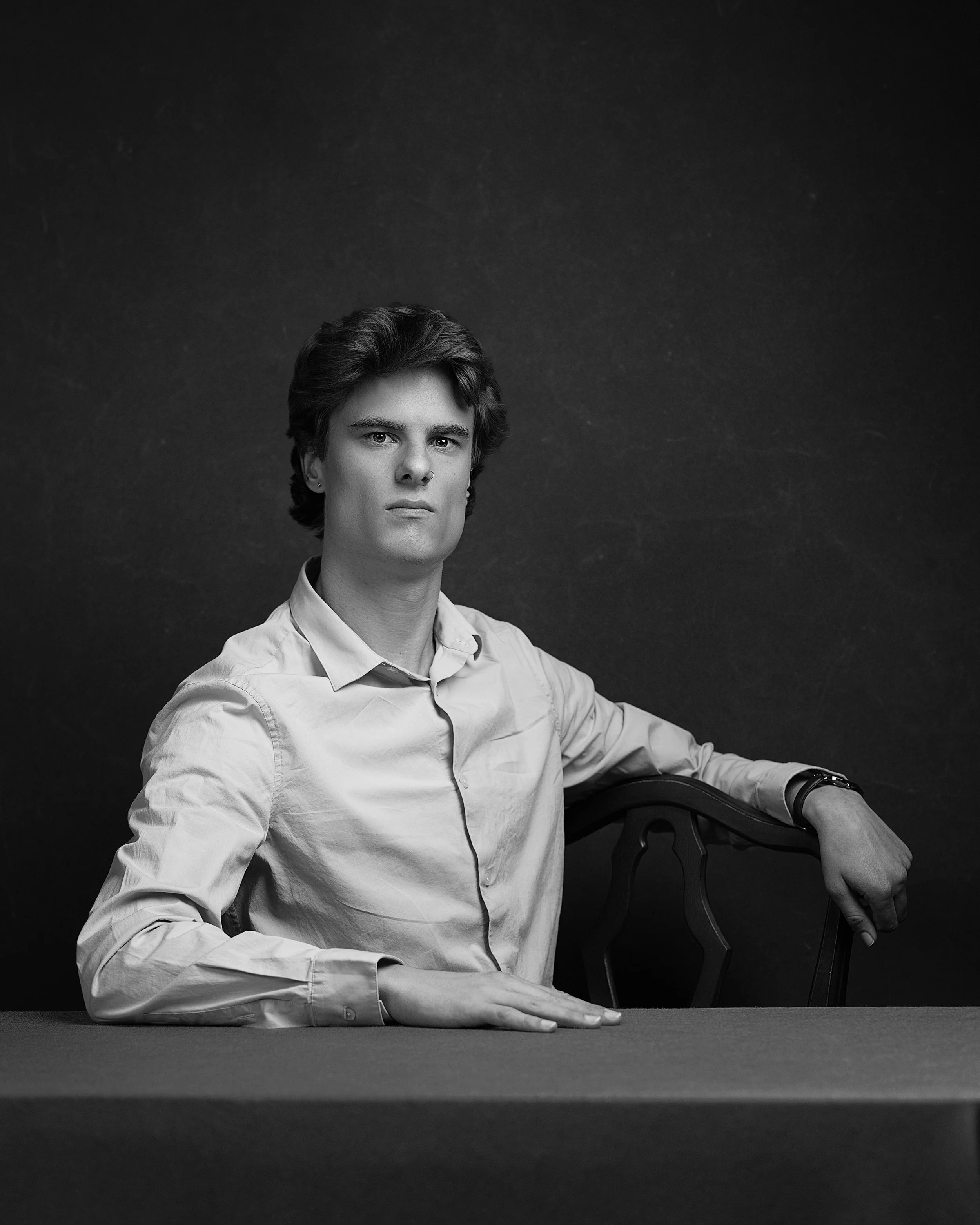 black and white photo of man at a table sitting sideways