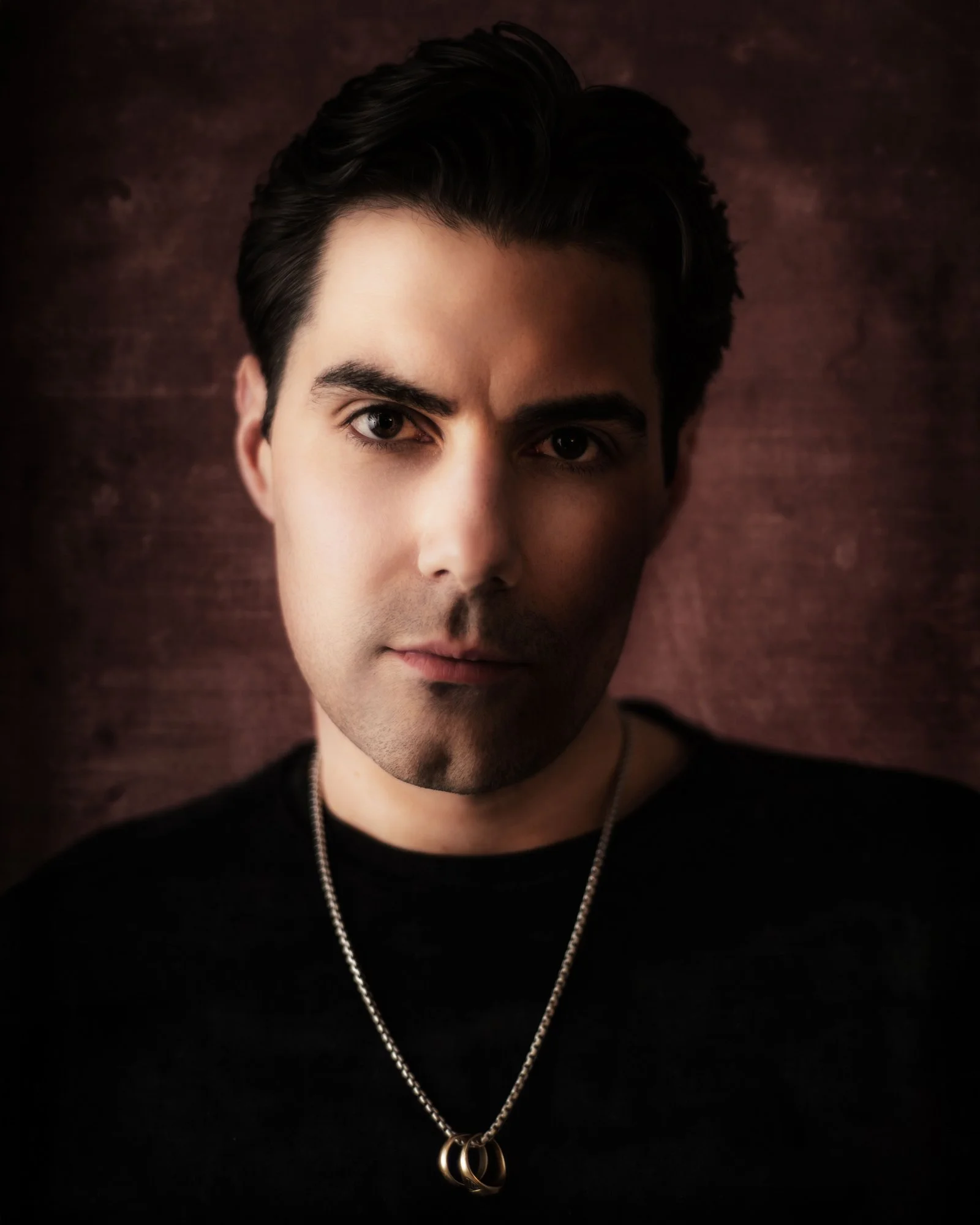portrait of man with chain black shirt red backdrop