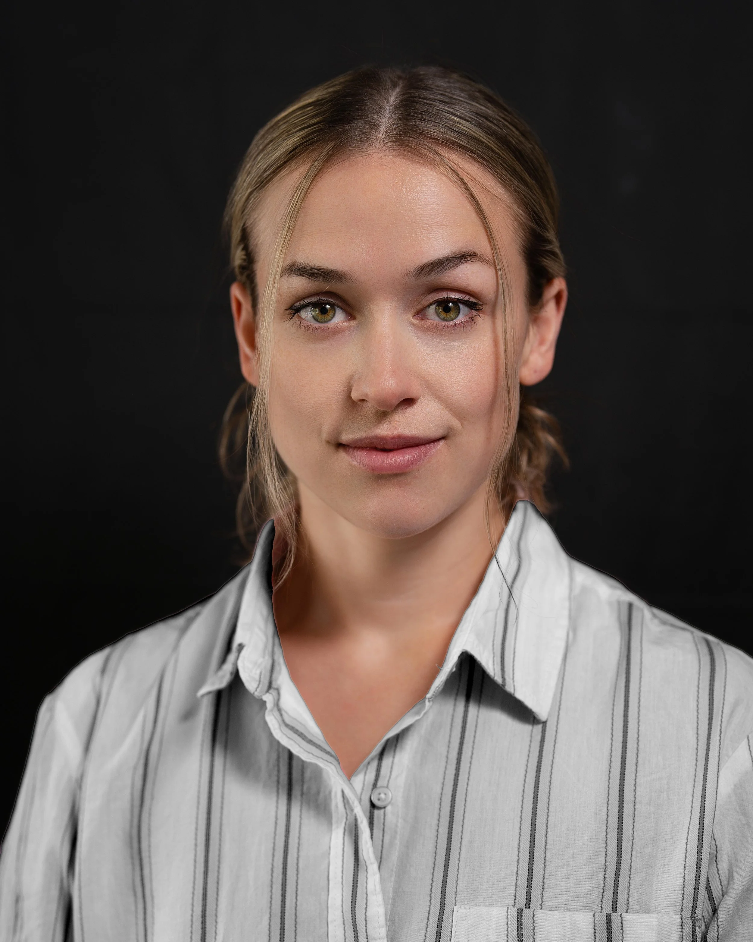 Portrait headshot of female actor with white striped shirt and black backdrop
