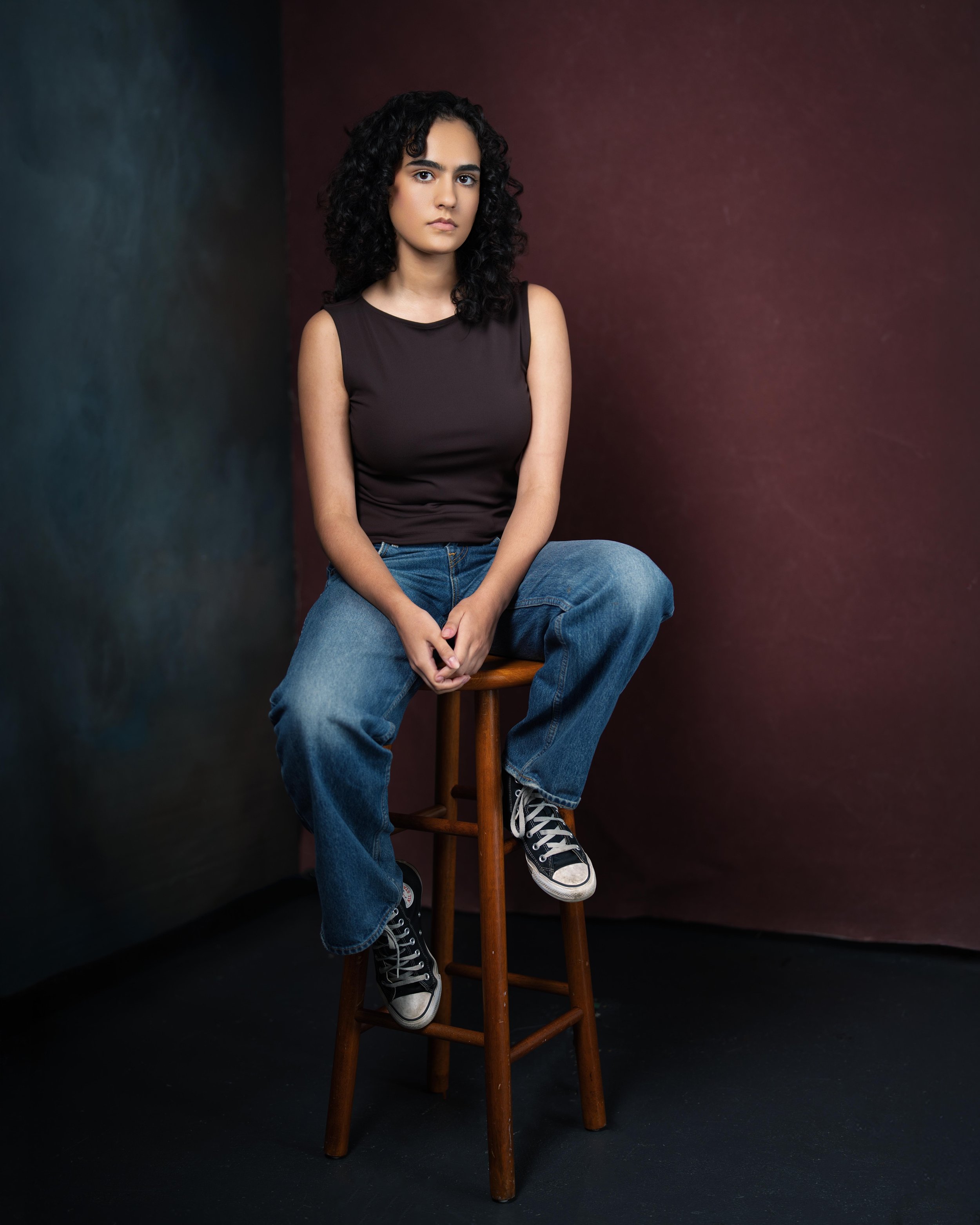 Portrait of brown actor sitting on wooden stool