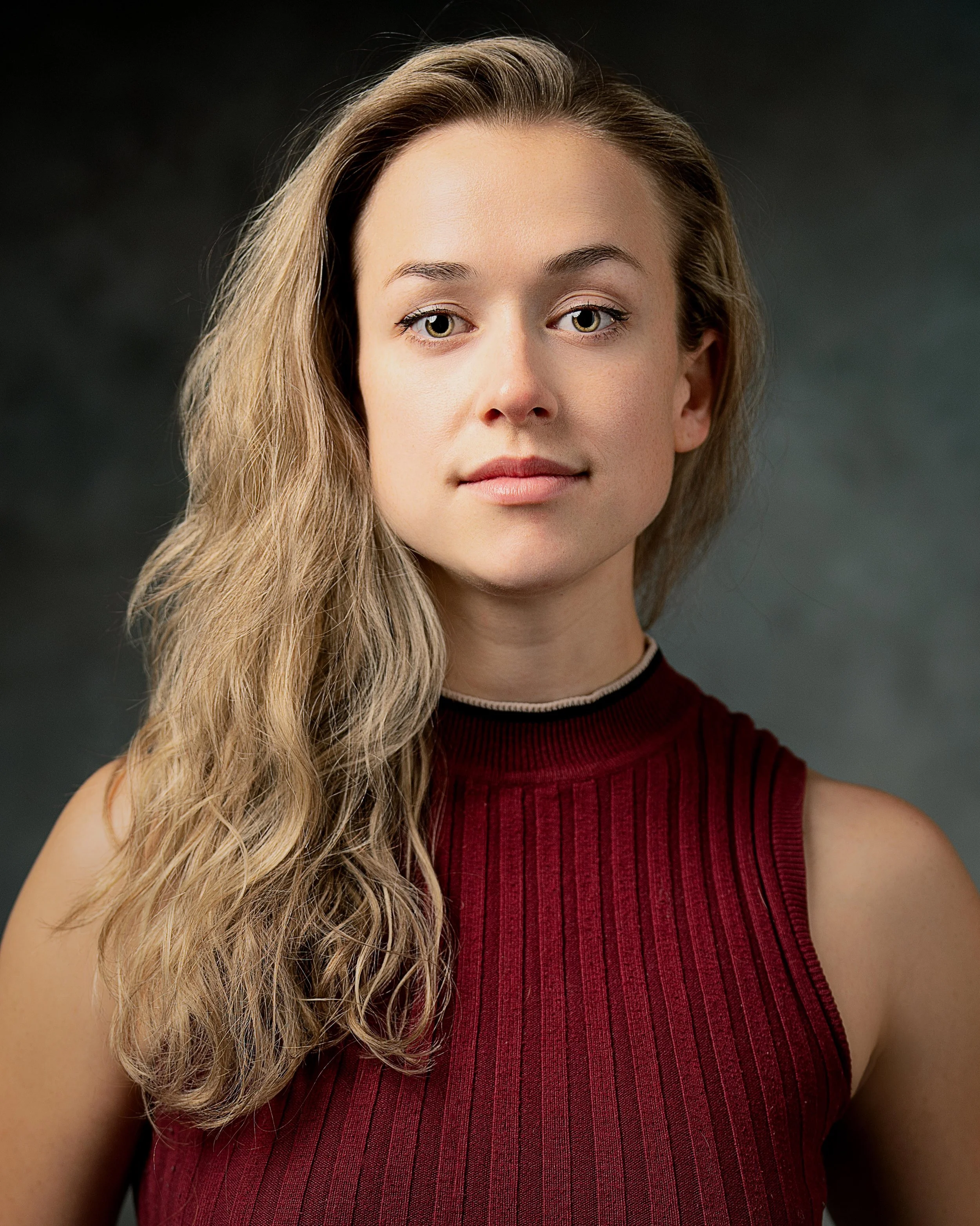 Portrait headshot of female actor in red with hair down and curly