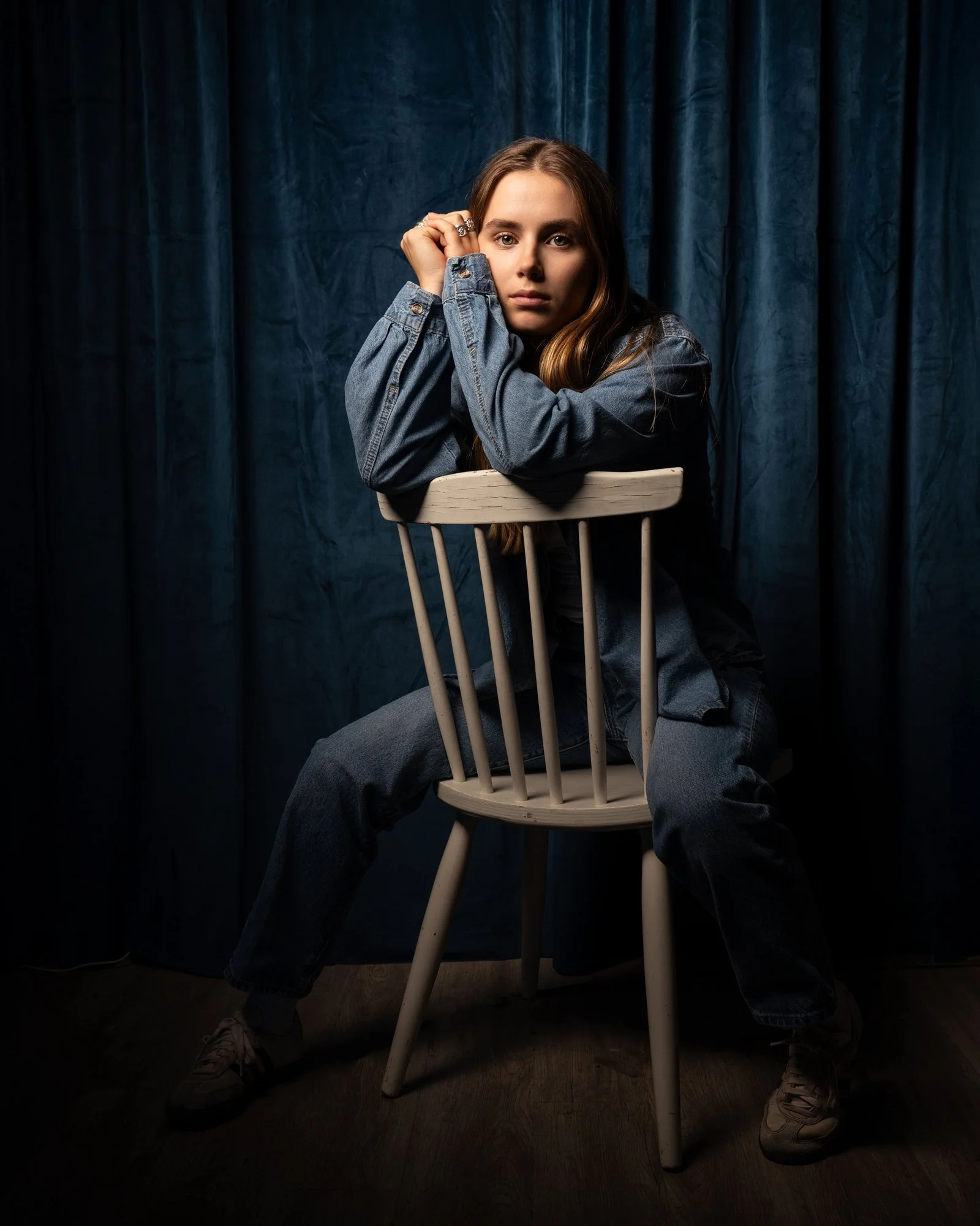 portrait of woman in blue jean outfit white shirt sitting backwards in chair