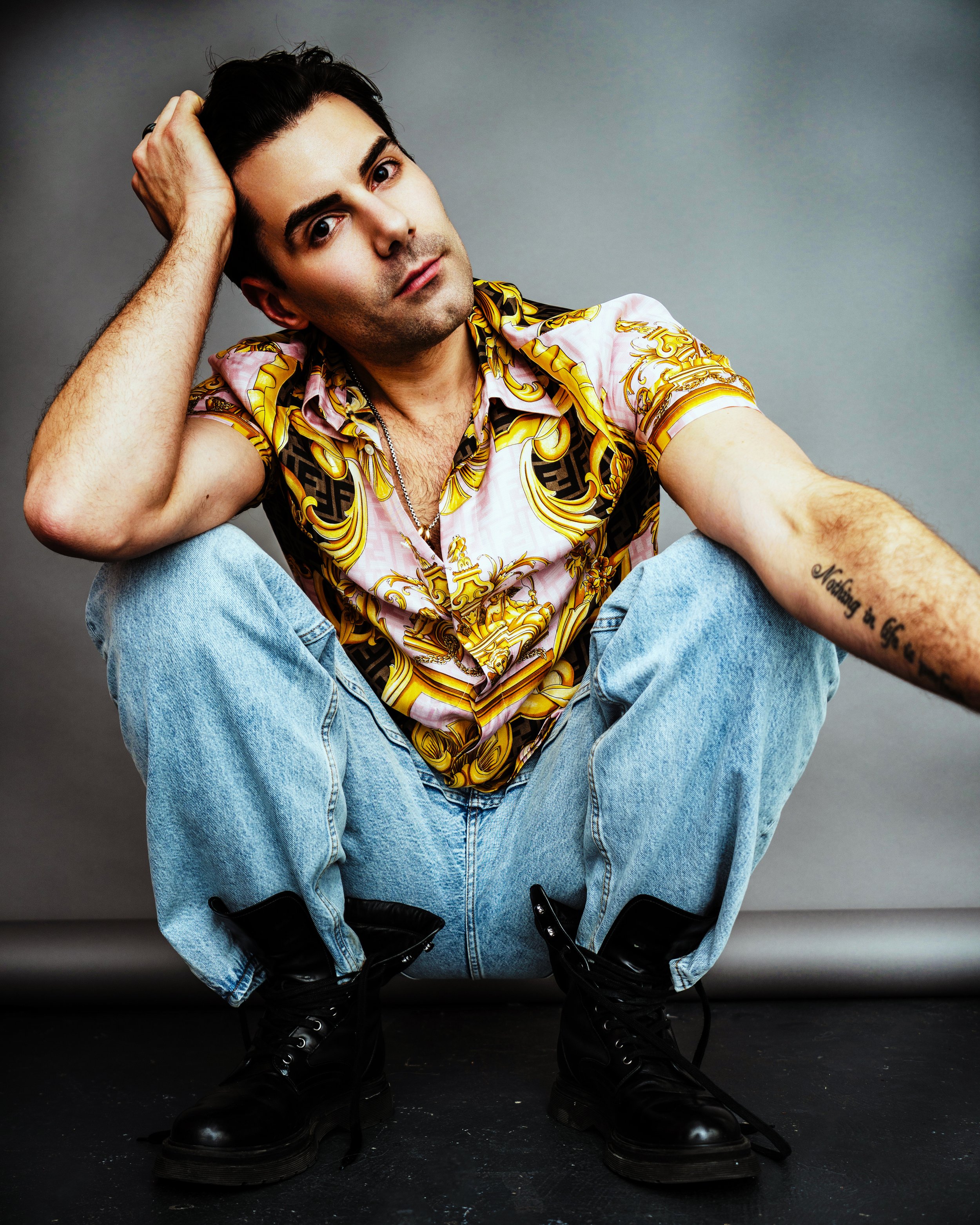 portrait of a man squatting in yellow top and blue jeans