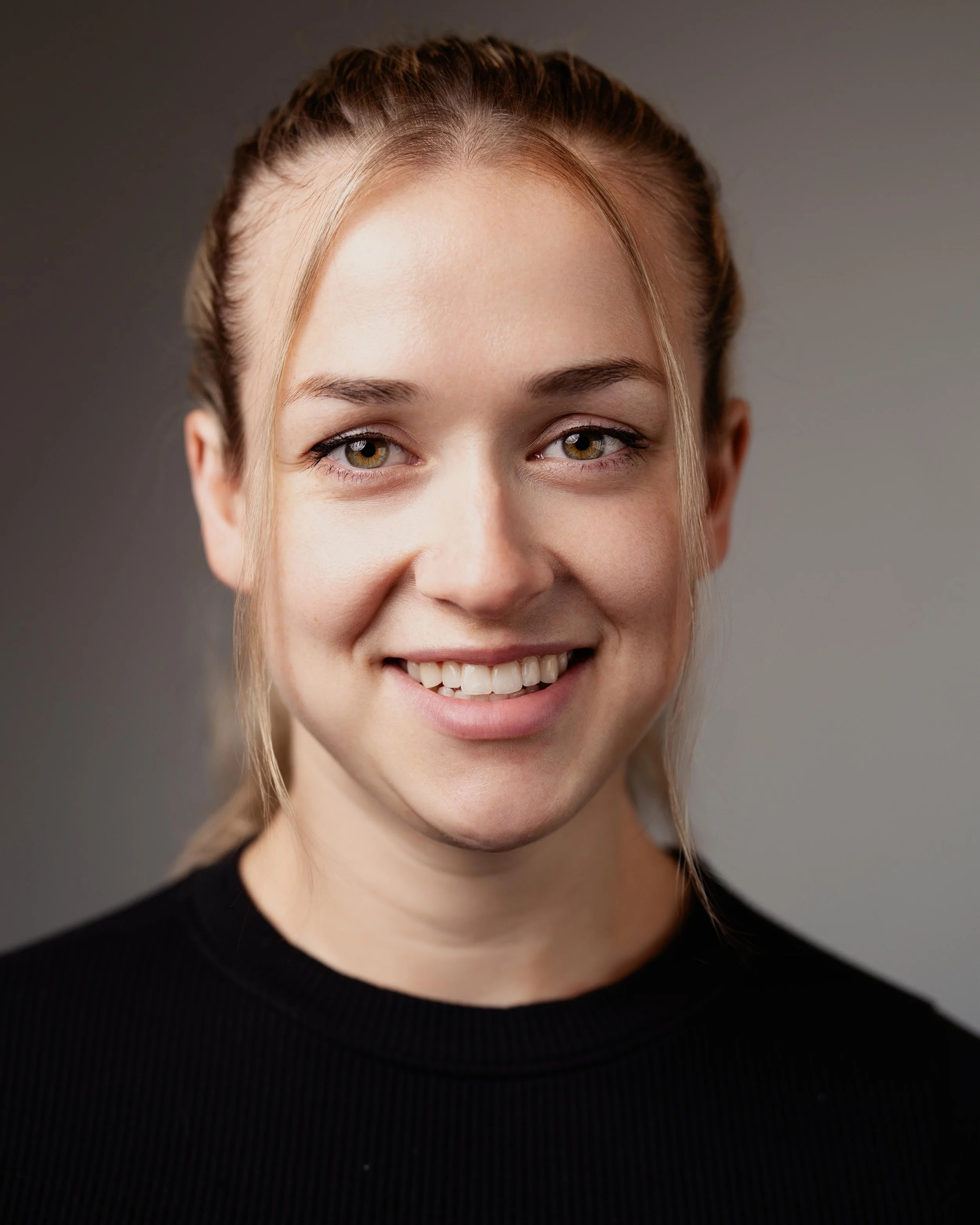Portrait headshot of female actor smiling in black shirt white brown backdrop