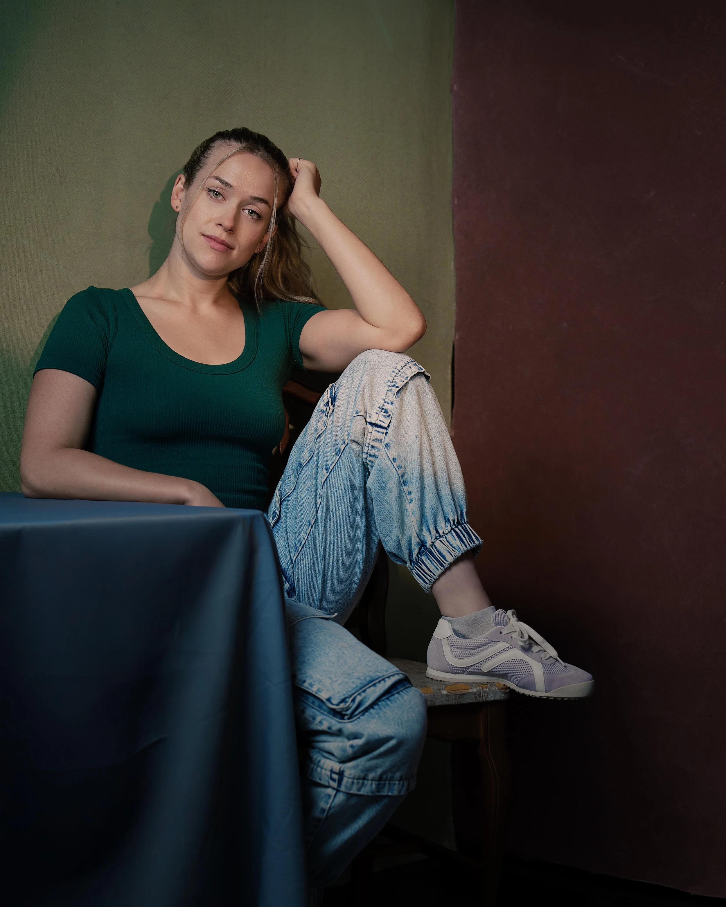 Portrait headshot of female actor in green shirt blue table red and green backdrop