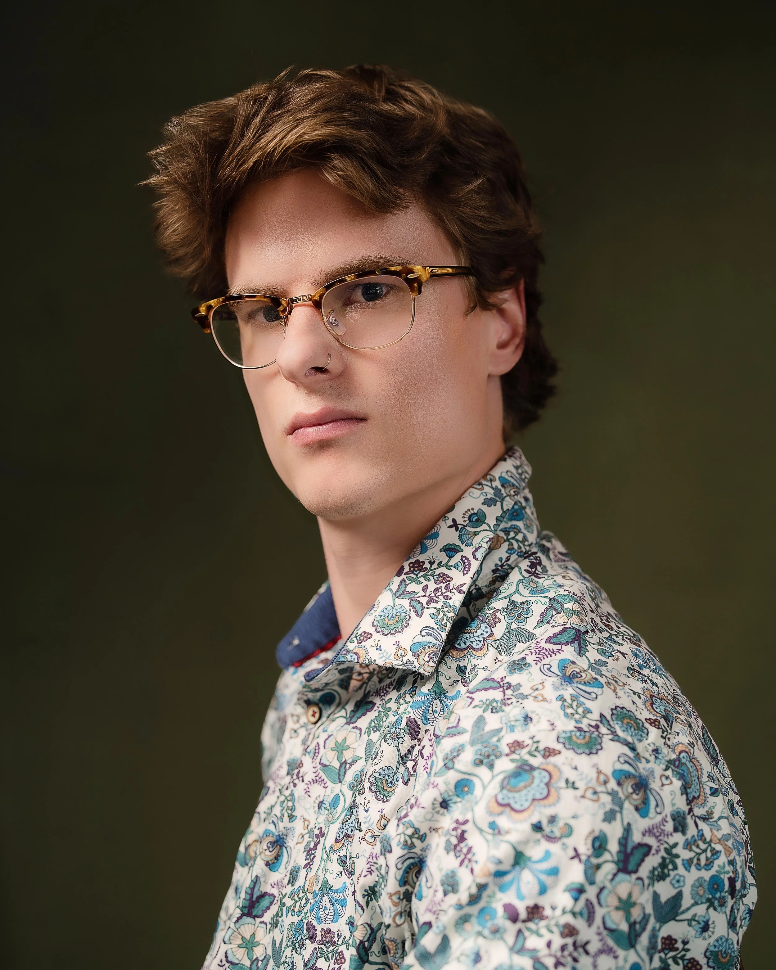 Portrait of man in patterned shirt with olive green backdrop