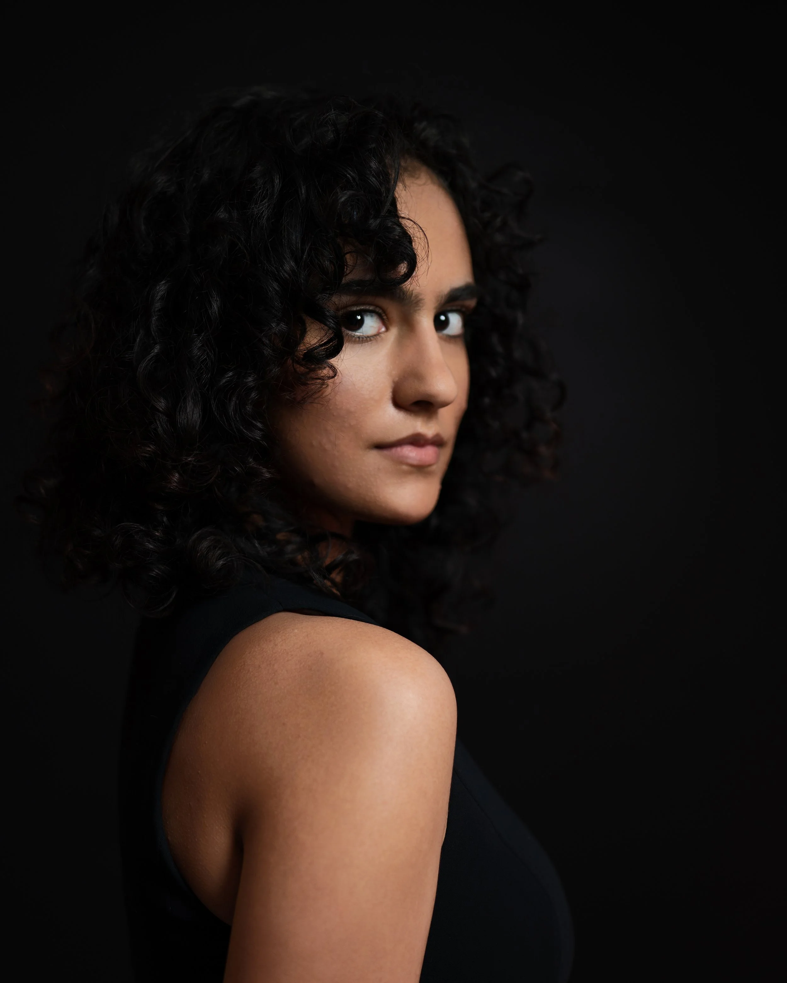 Headshot of brown actor looking over shoulder
