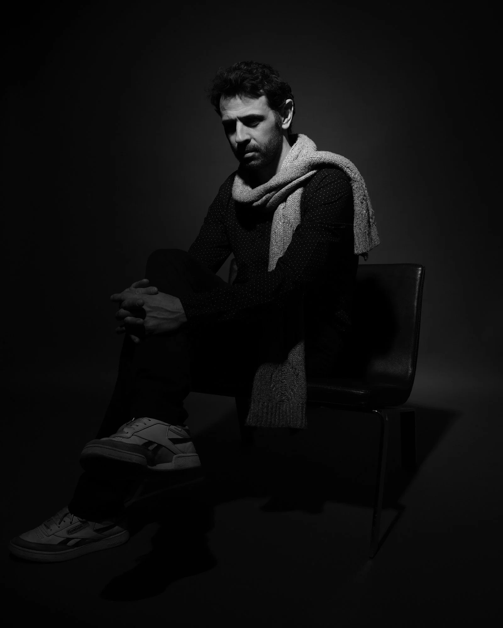 black portrait of man in scarf sitting in chair