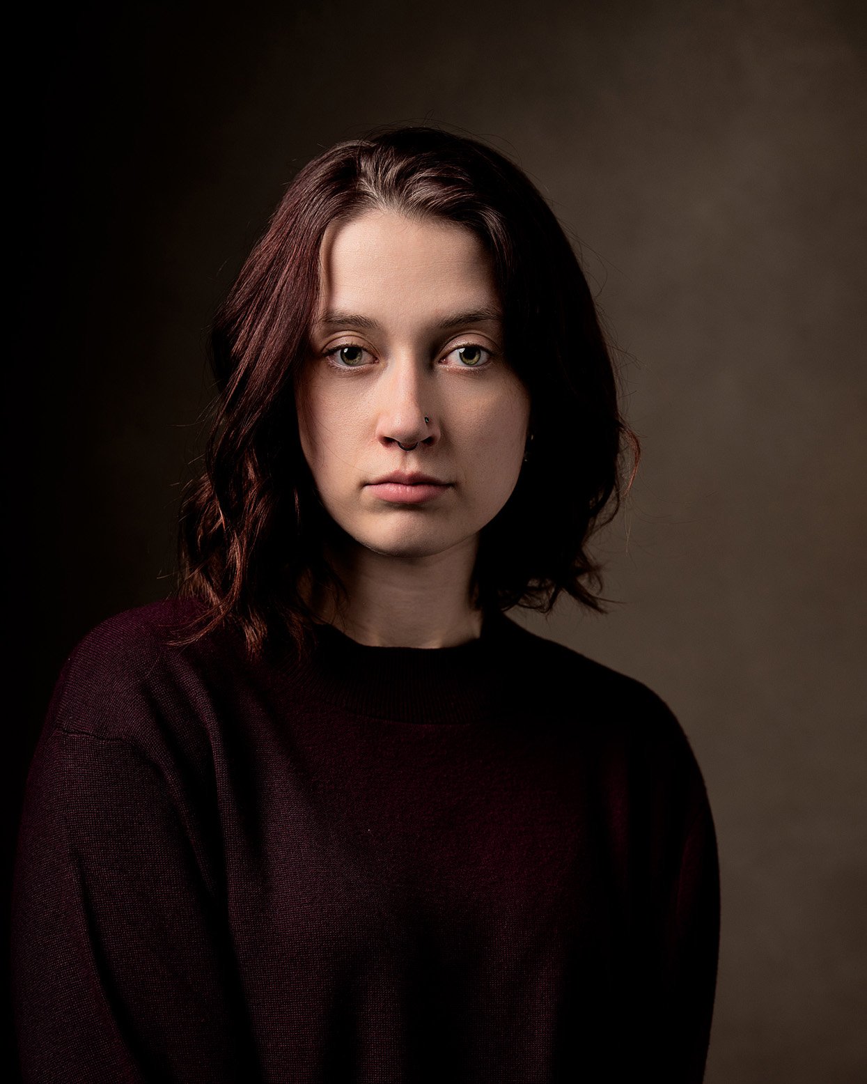 Headshot of a woman with auburn hair and a maroon sweater in front of a kaki backdrop