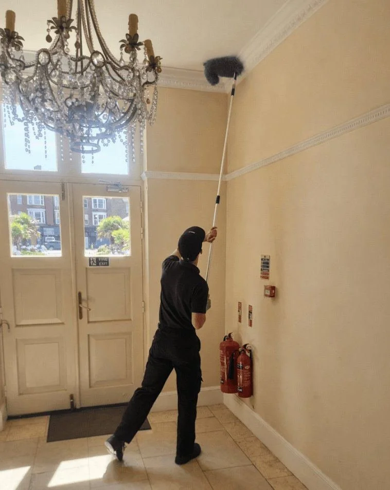Sphere Cleaning Services operative dusting communal entrance hall in residential block in London