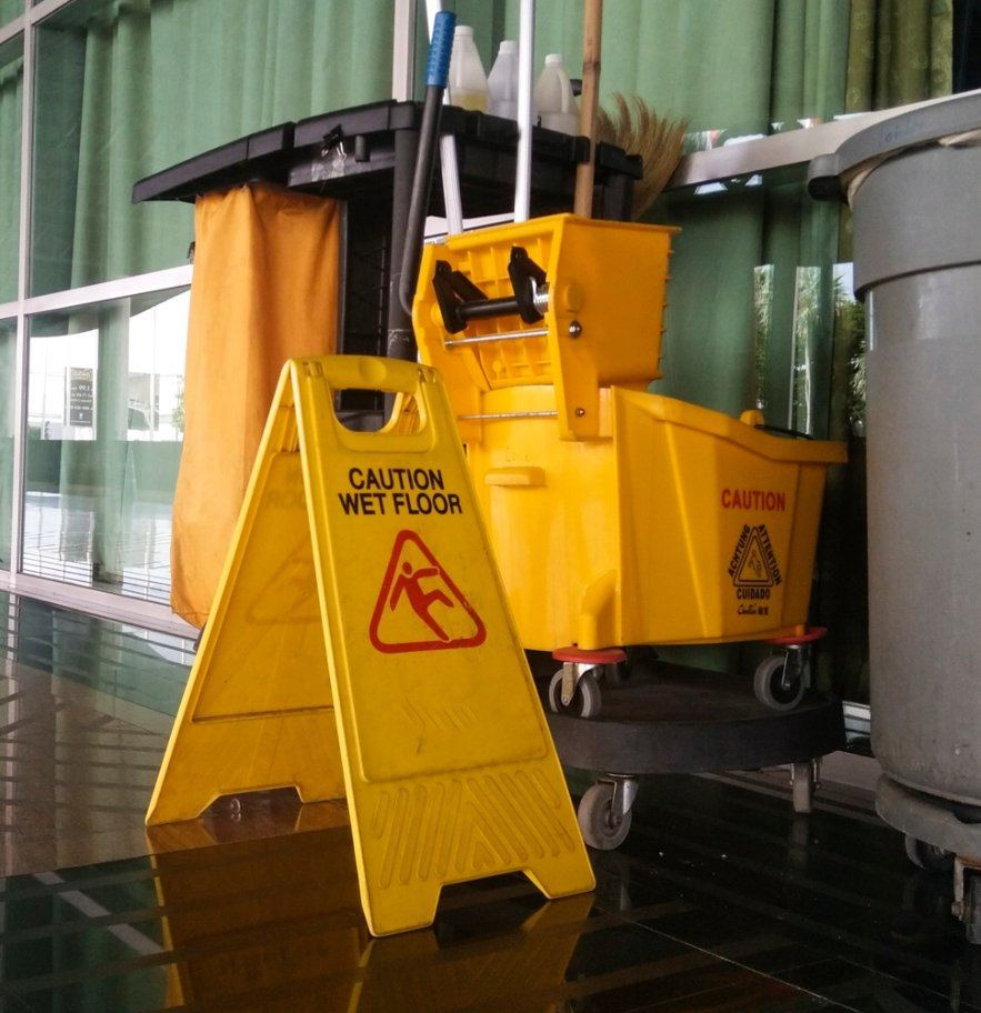 Communal cleaning equipment and wet floor sign in residential block corridor — Sphere Cleaning Services