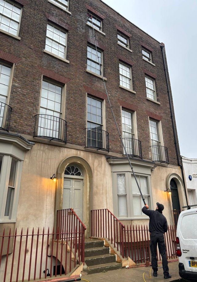 Professional window cleaner in Canterbury using a water-fed pole to clean windows on a Georgian terraced building